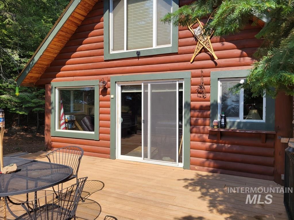 Back of property with faux log siding, outdoor dining space, and a wooden deck