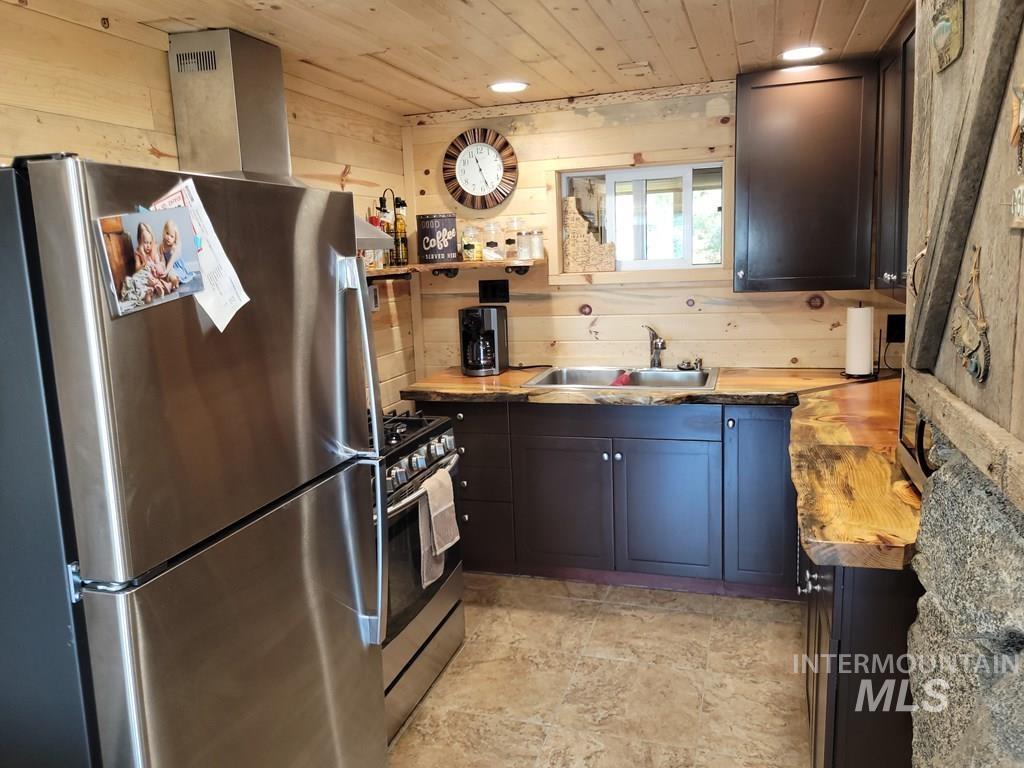 Kitchen with stainless steel appliances, wooden walls, and wood ceiling