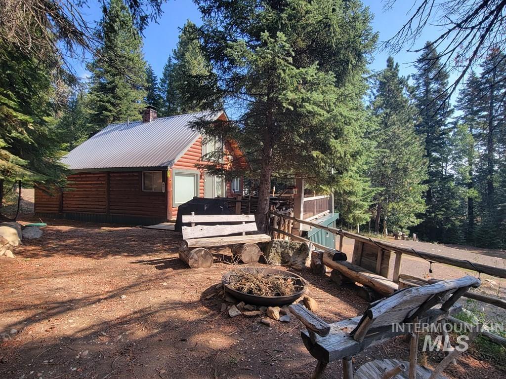 View of home's exterior featuring a metal roof, a chimney, faux log siding, a wooden deck, and a garage