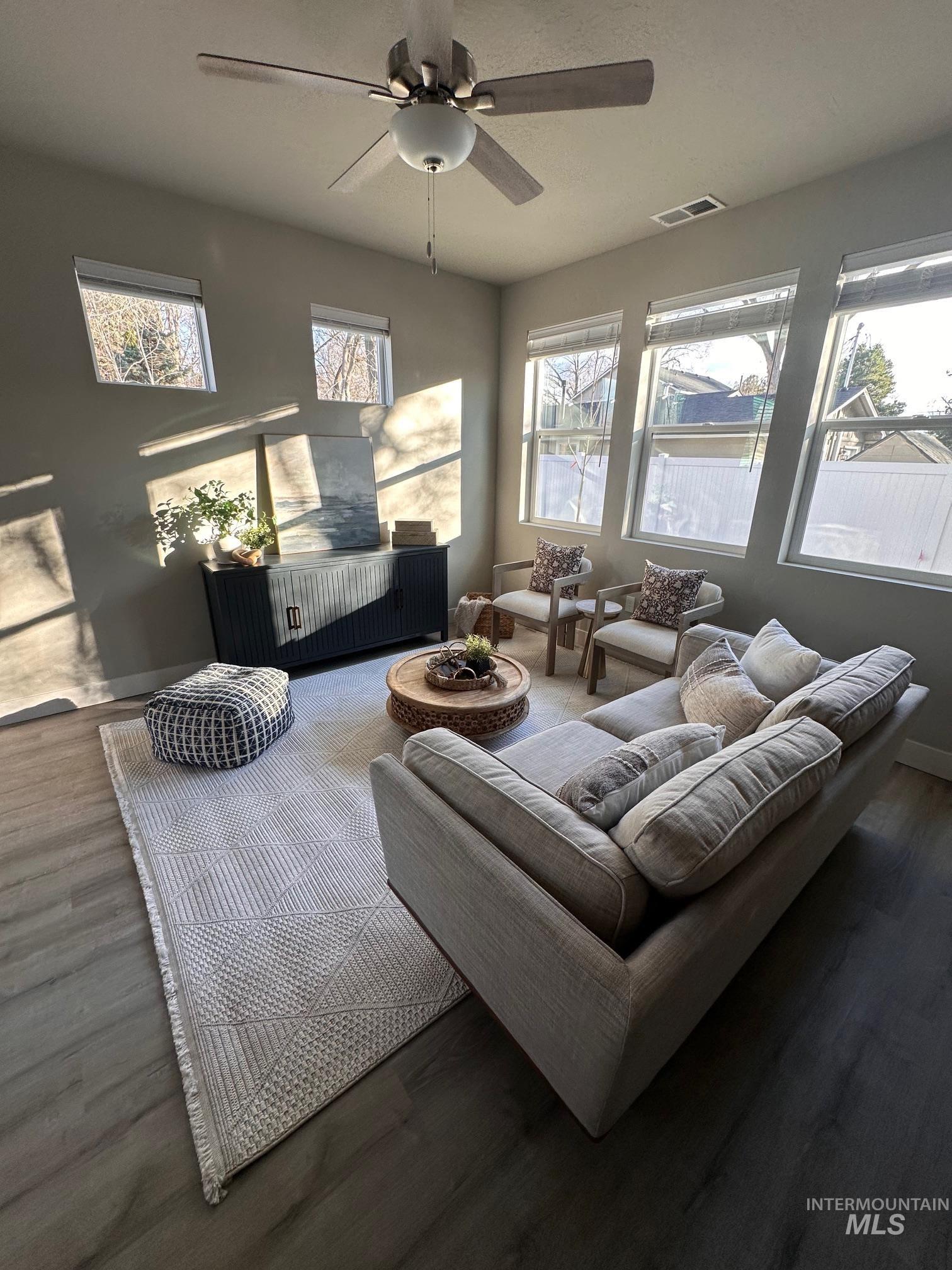 Living room with dark wood-type flooring and a ceiling fan
