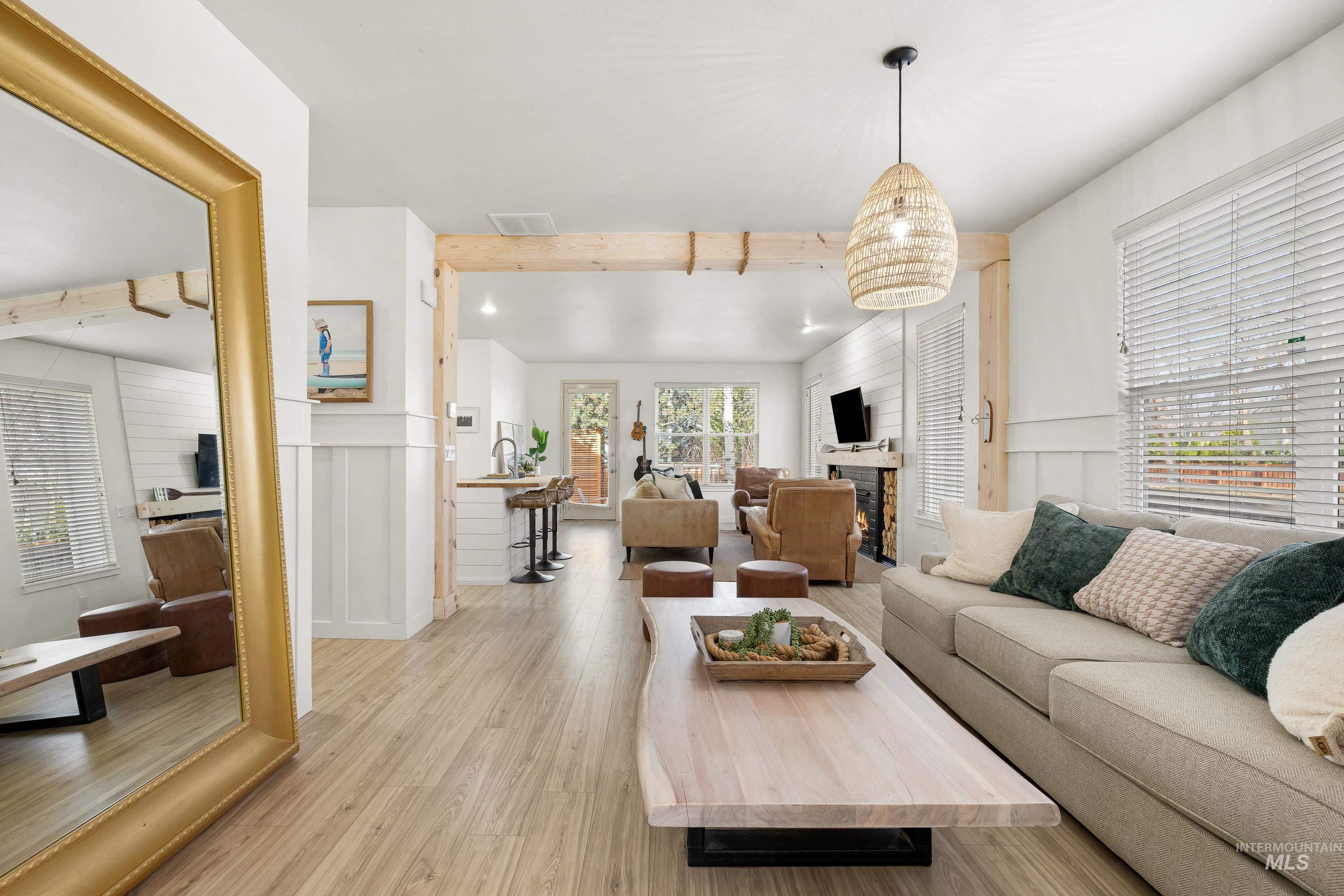 Living area featuring light wood-style flooring, a decorative wall, a fireplace, and a wainscoted wall