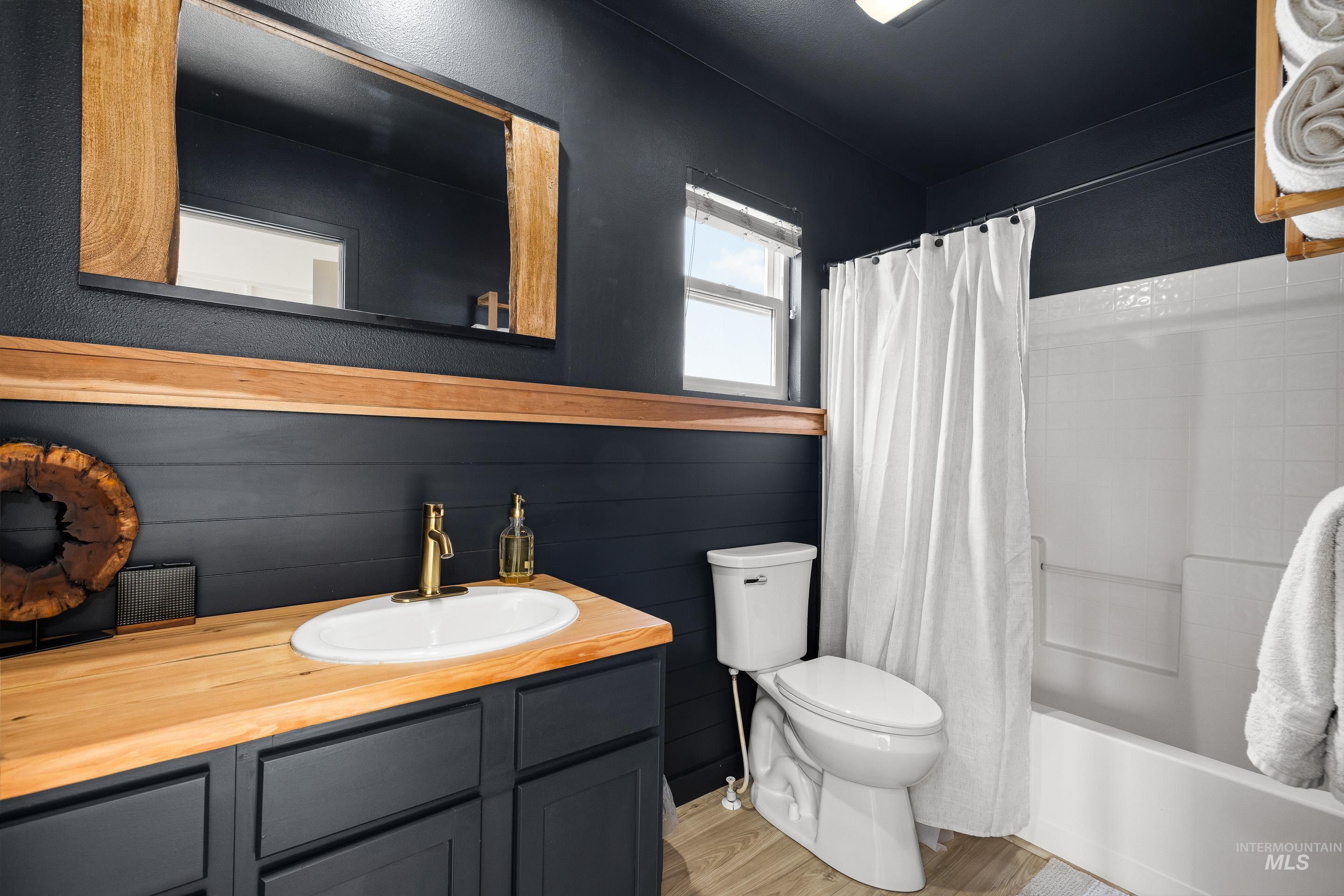 Bathroom with vanity, shower / bath combo, and light wood-style floors