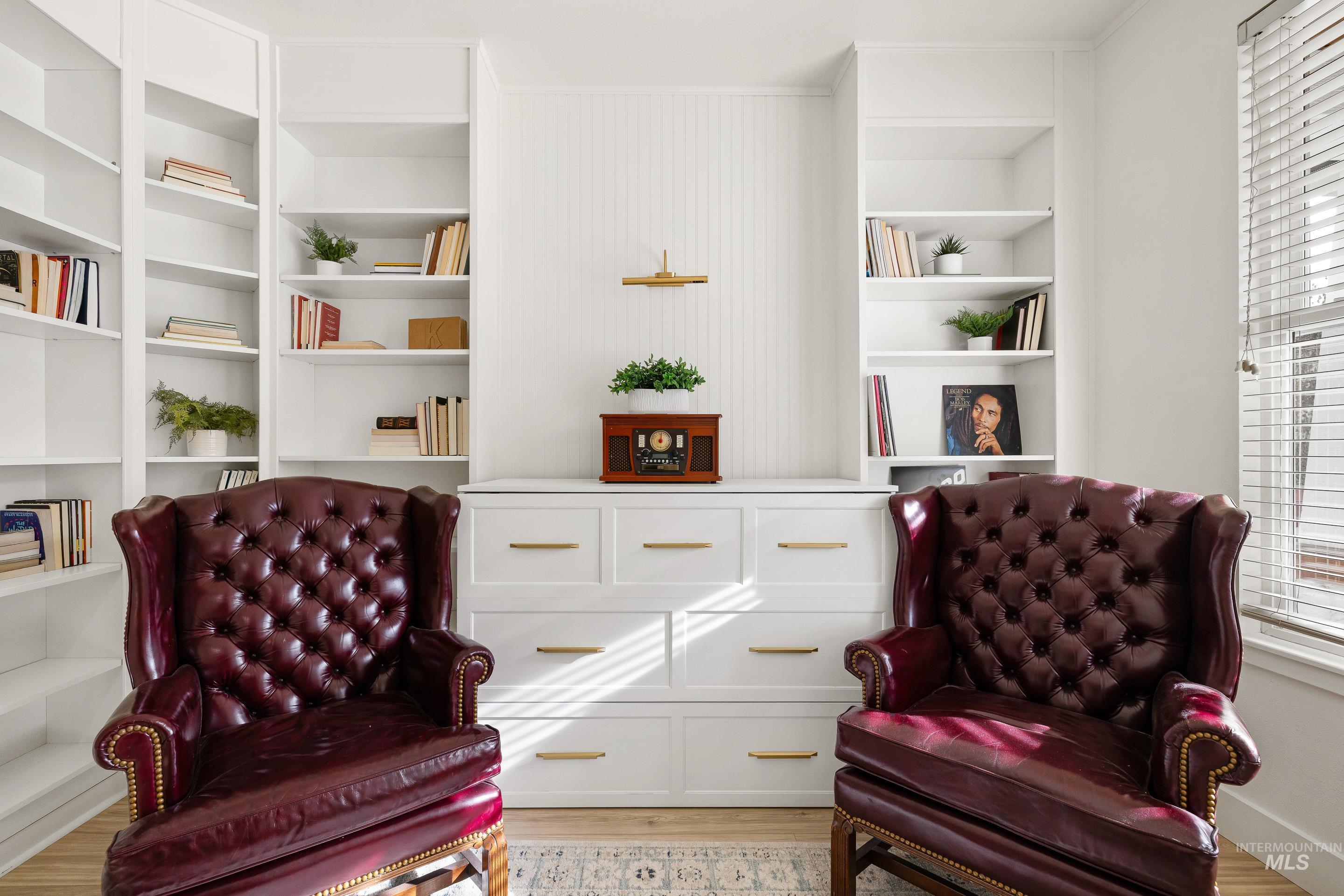 Sitting room featuring built in shelves, light wood-style flooring, and plenty of natural light