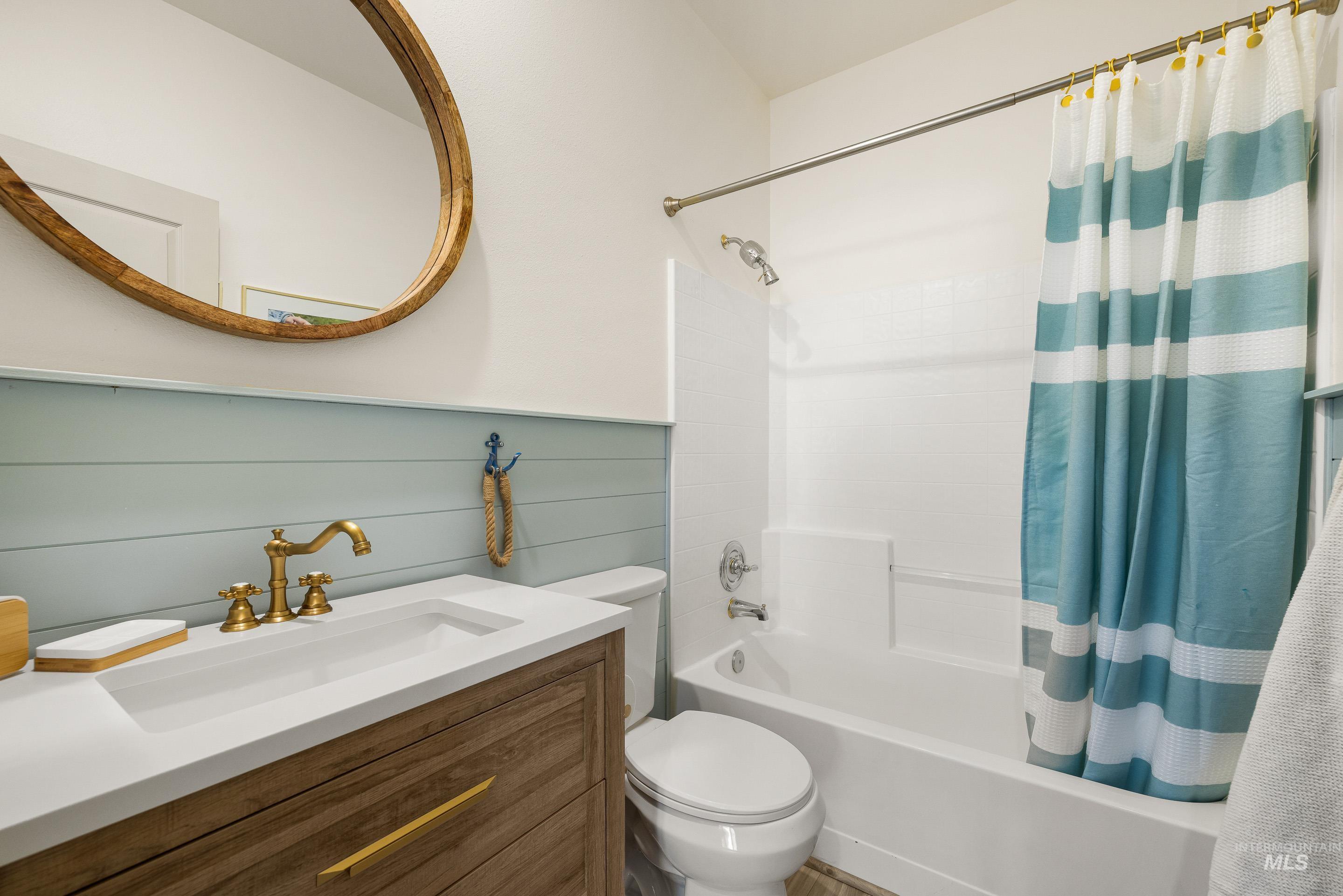 Full bath featuring vanity, shower / bath combo, and wooden walls