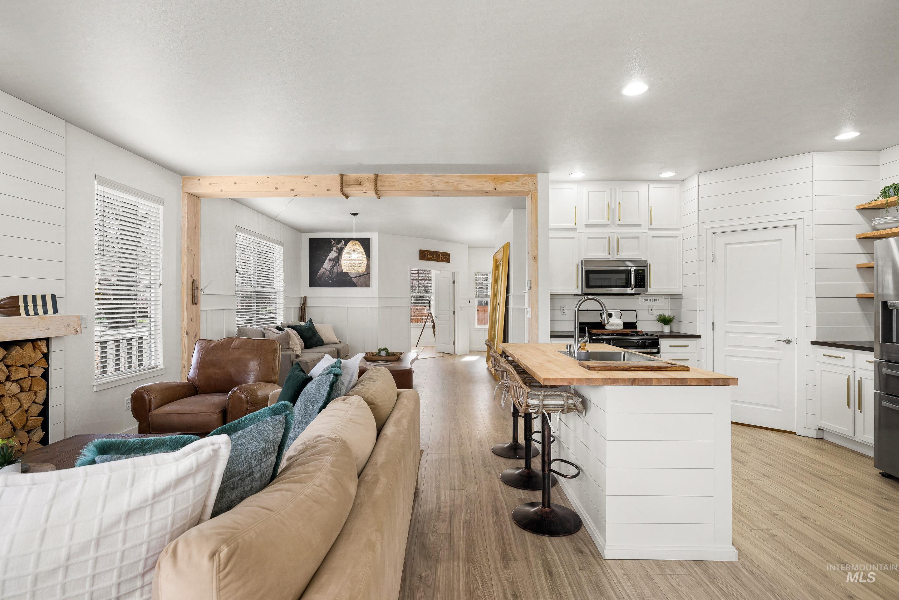 Living room with light wood finished floors, wooden walls, beamed ceiling, and recessed lighting