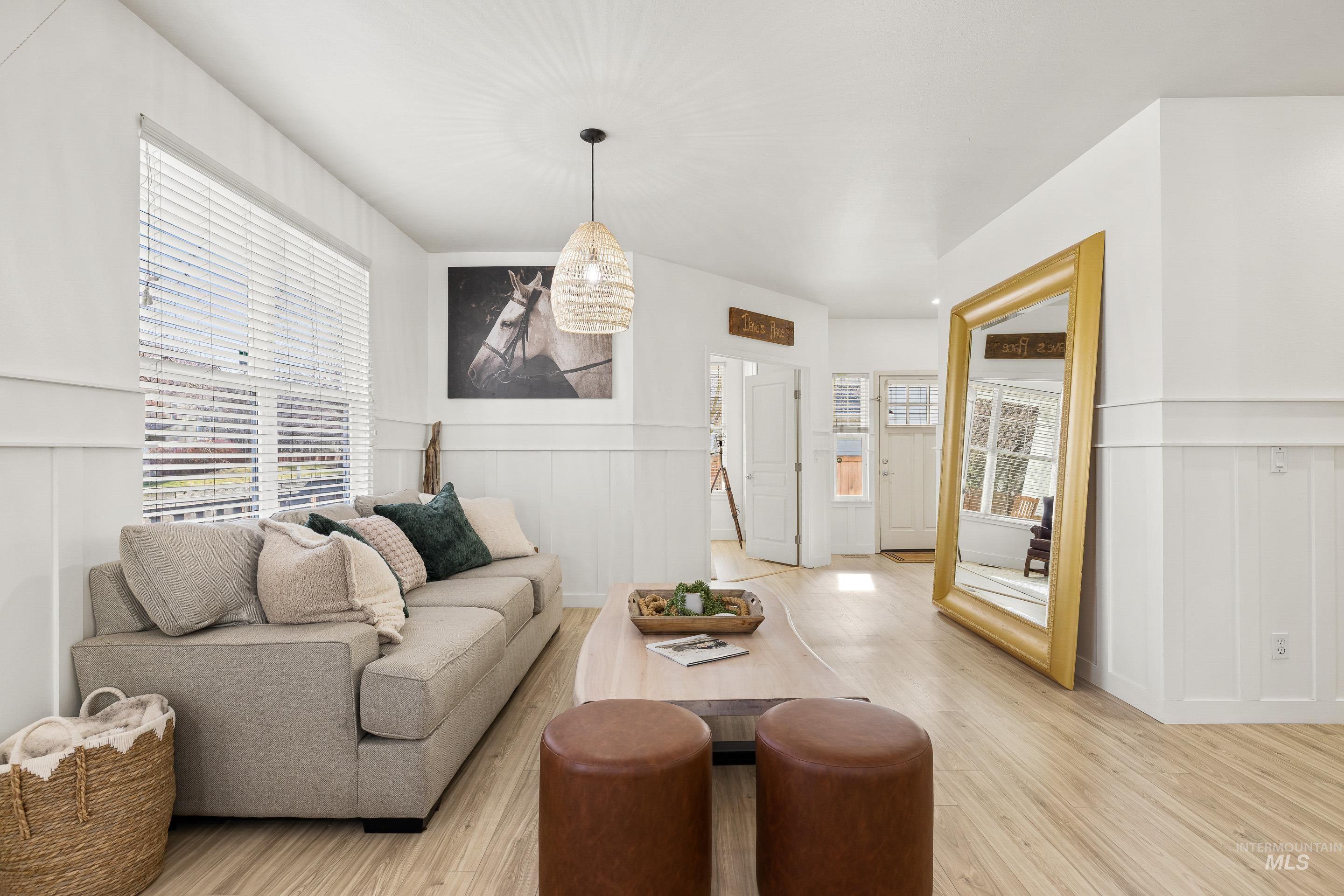 Living area with a wainscoted wall, a decorative wall, and light wood-style flooring