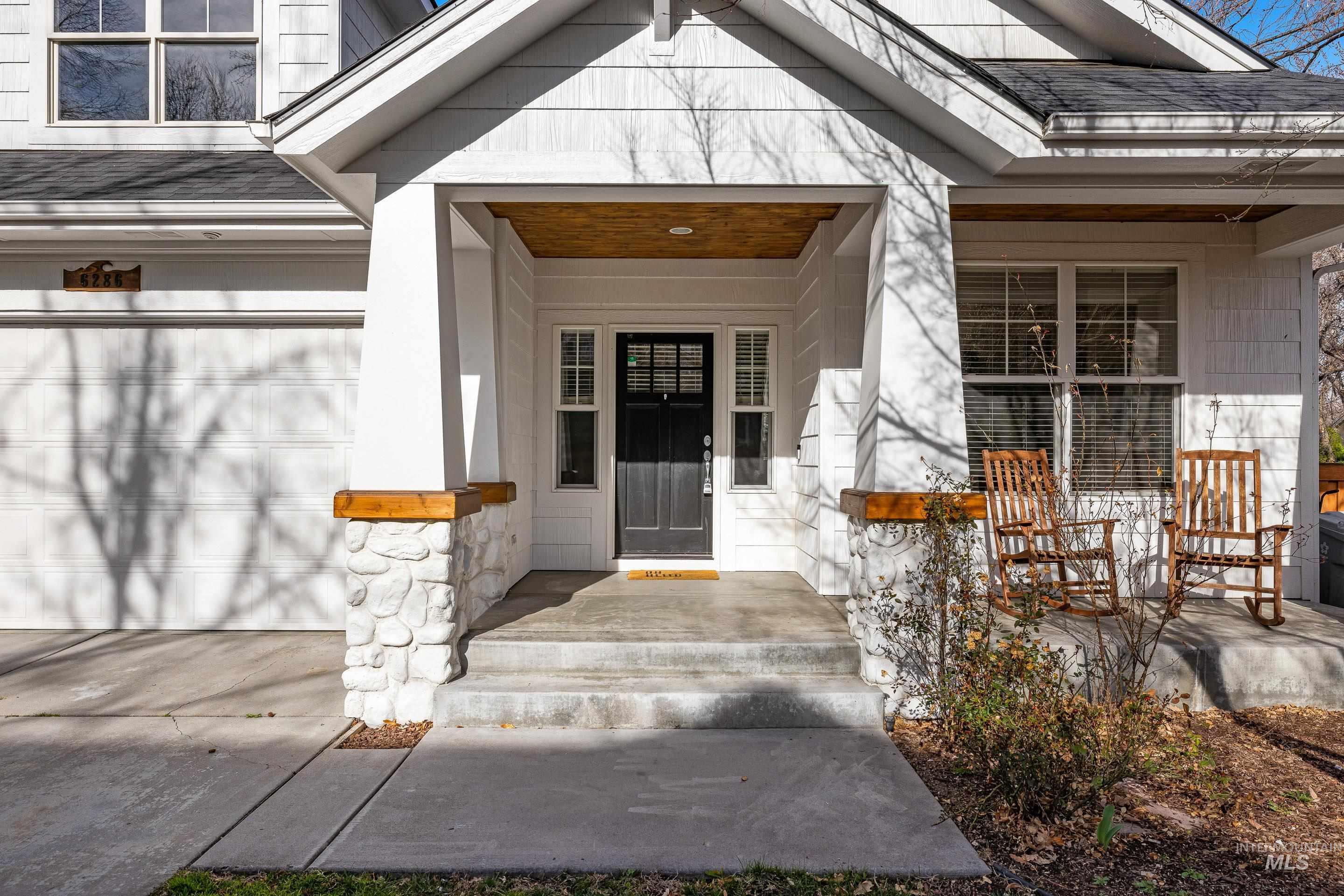 Property entrance featuring covered porch, roof with shingles, and concrete driveway