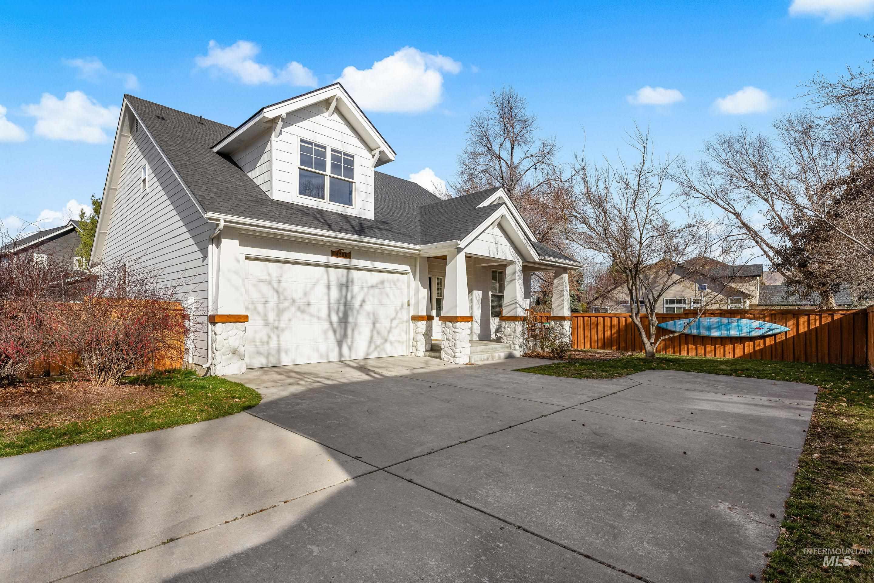 View of front of property with a shingled roof, stone siding, covered porch, and concrete driveway
