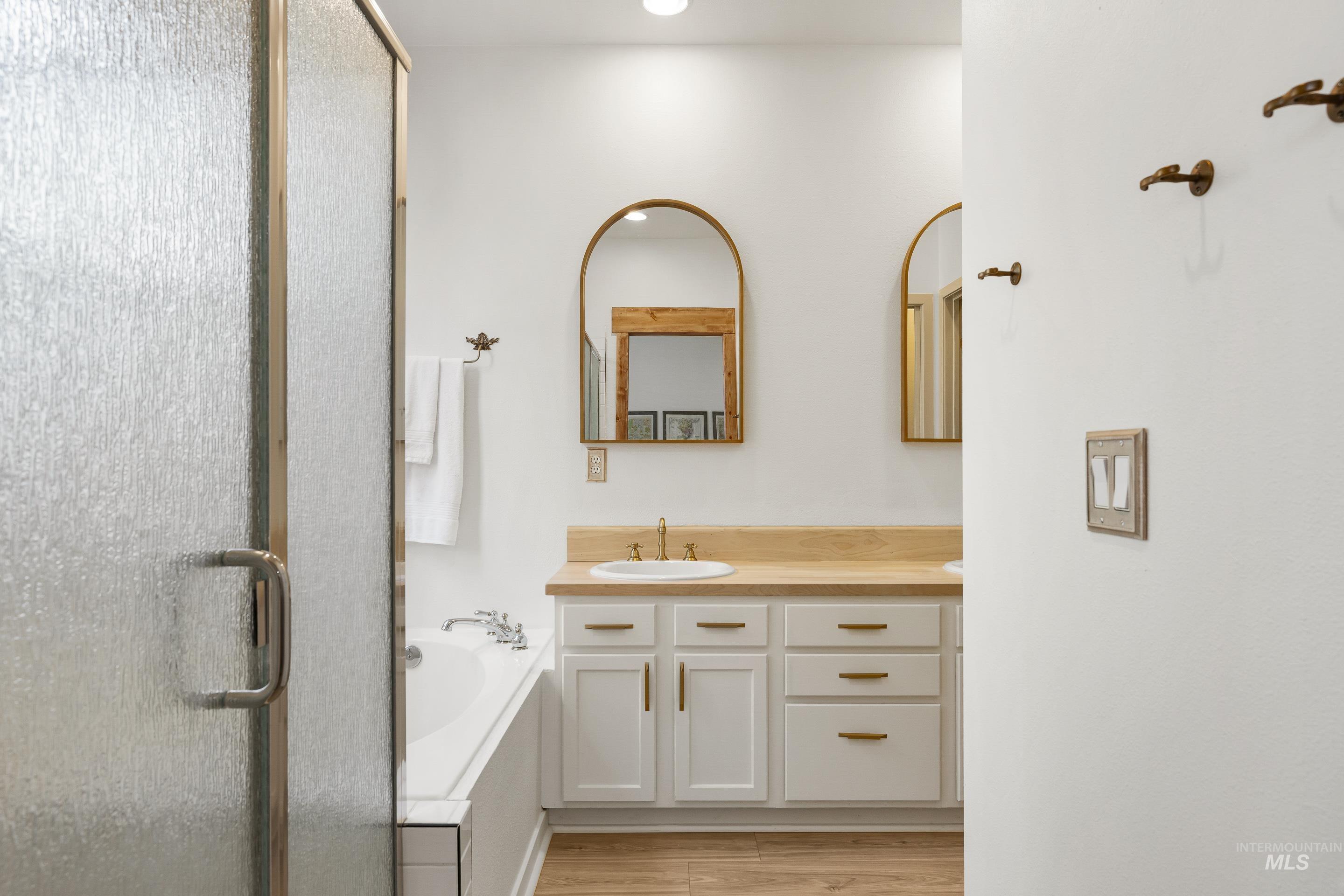Bathroom with vanity, a shower stall, a garden tub, and light wood finished floors