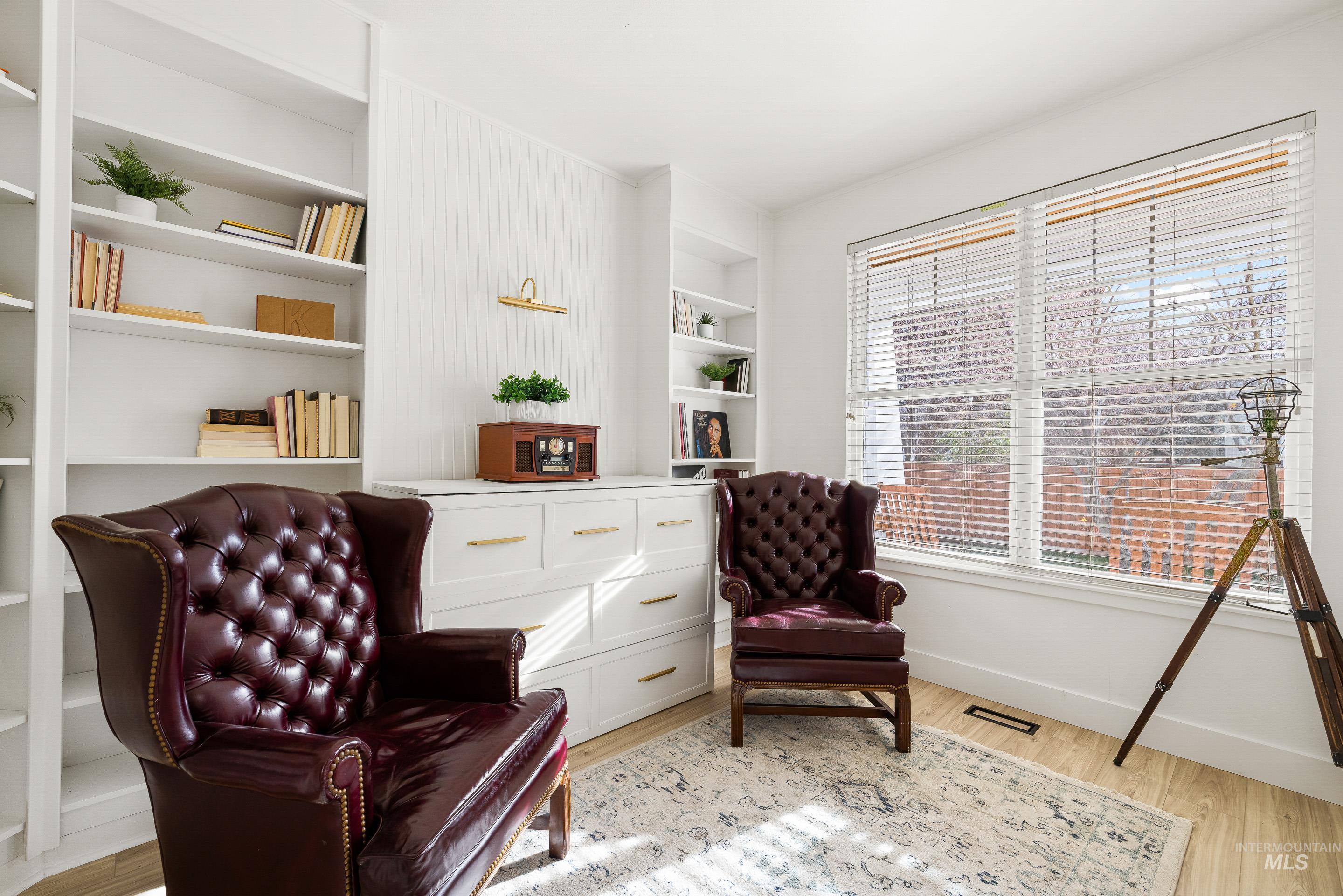 Sitting room with built in features and light wood-style floors