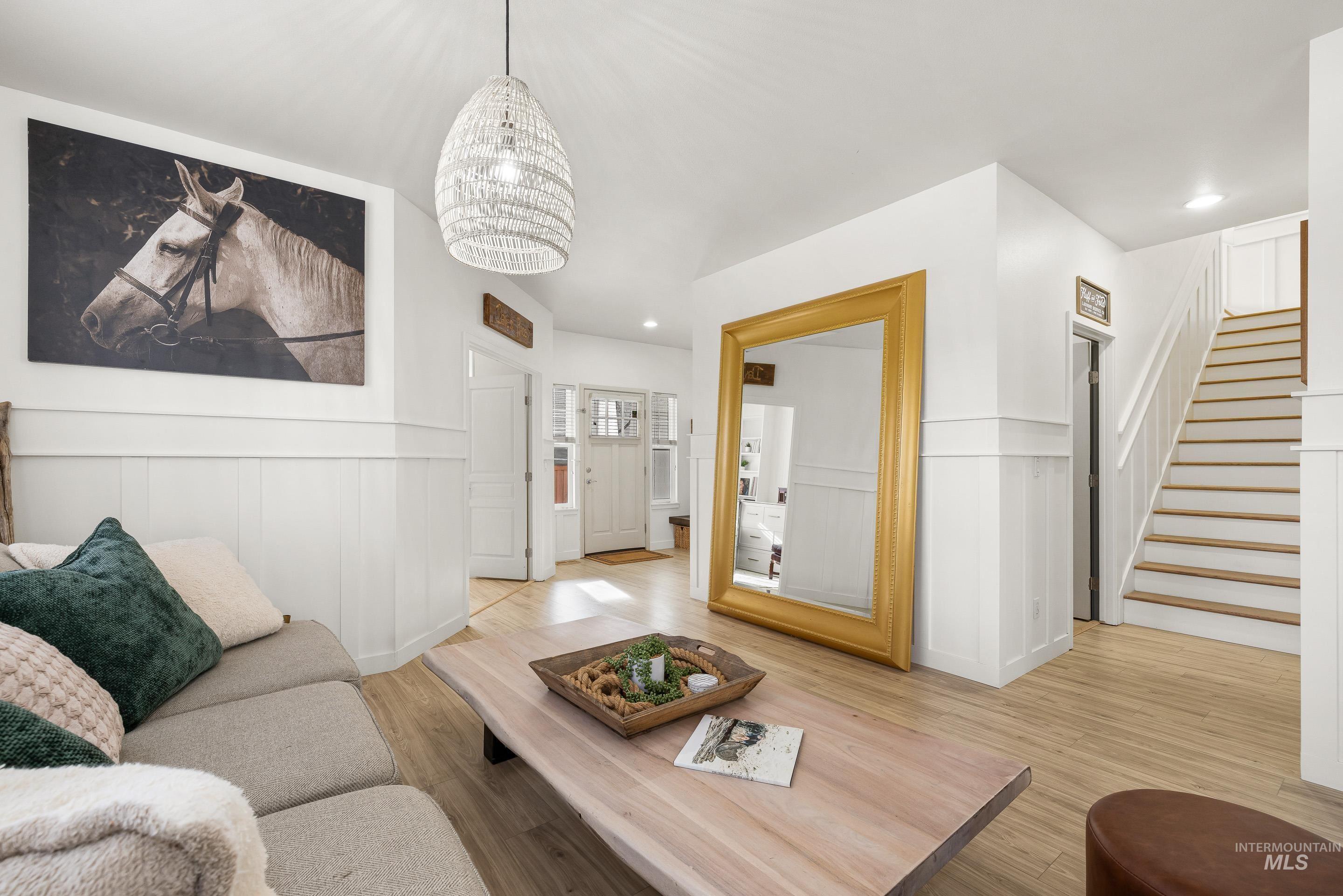 Living area with a wainscoted wall, light wood-type flooring, a decorative wall, and suspended lighting