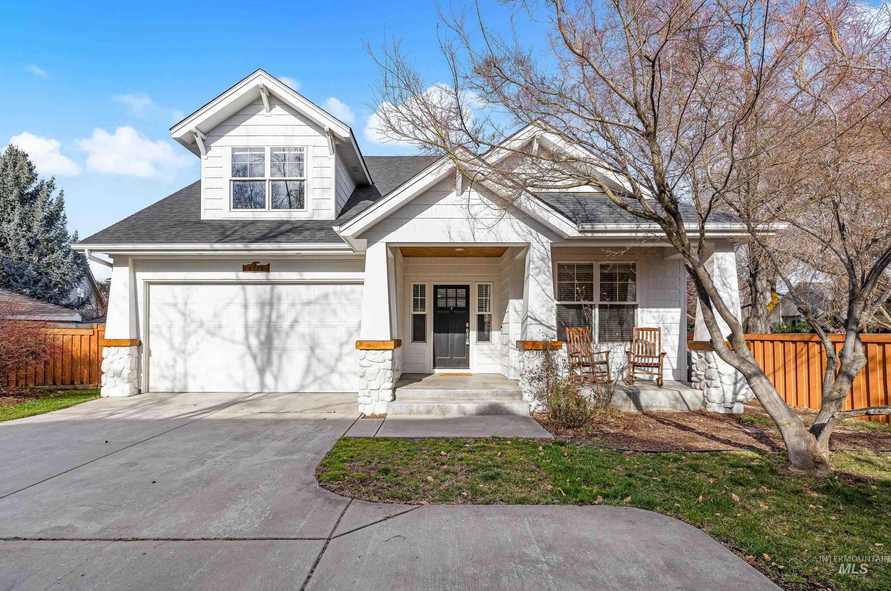 Craftsman-style home featuring a porch, concrete driveway, stone siding, and roof with shingles
