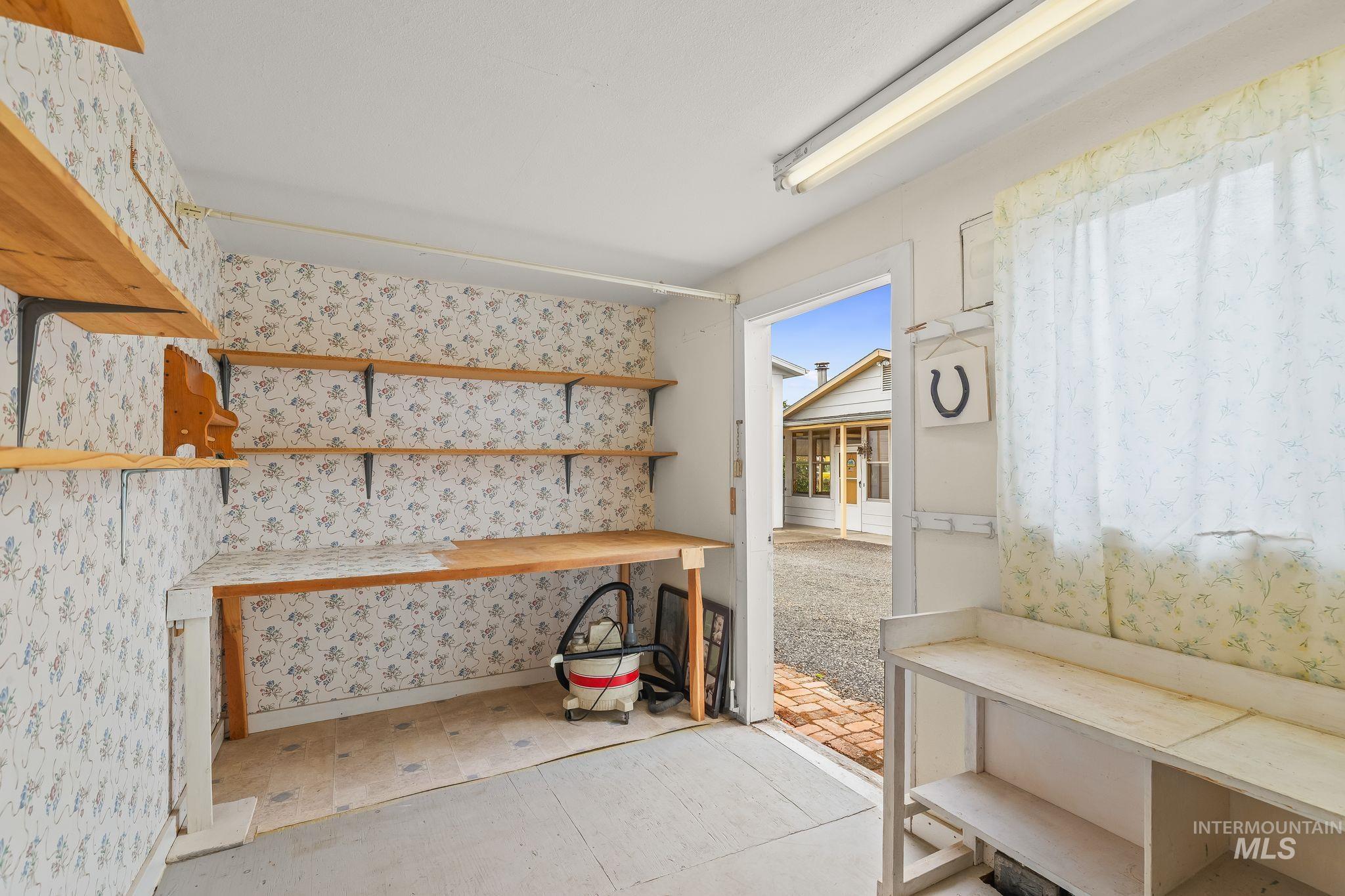 Utility room featuring built-in wood shelving, a built-in wood-finish workbench, and a white ceiling-mounted fluorescent light fixture