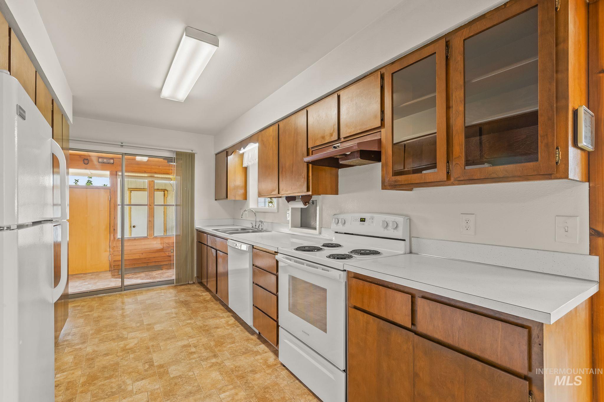 Kitchen featuring wood cabinetry, white countertops, and white appliances
