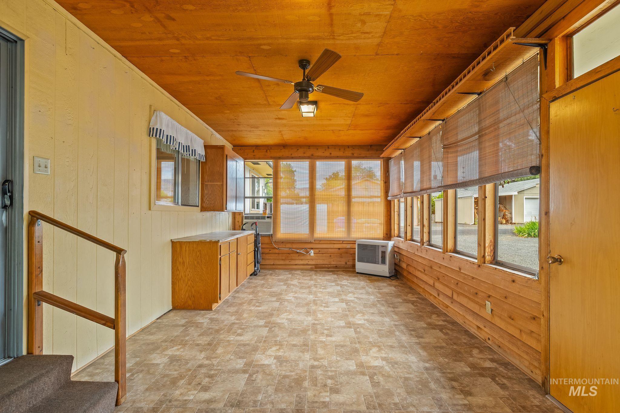 Enclosed sunroom featuring wood-finish flooring, wood plank ceiling, and a ceiling fan with integrated lighting