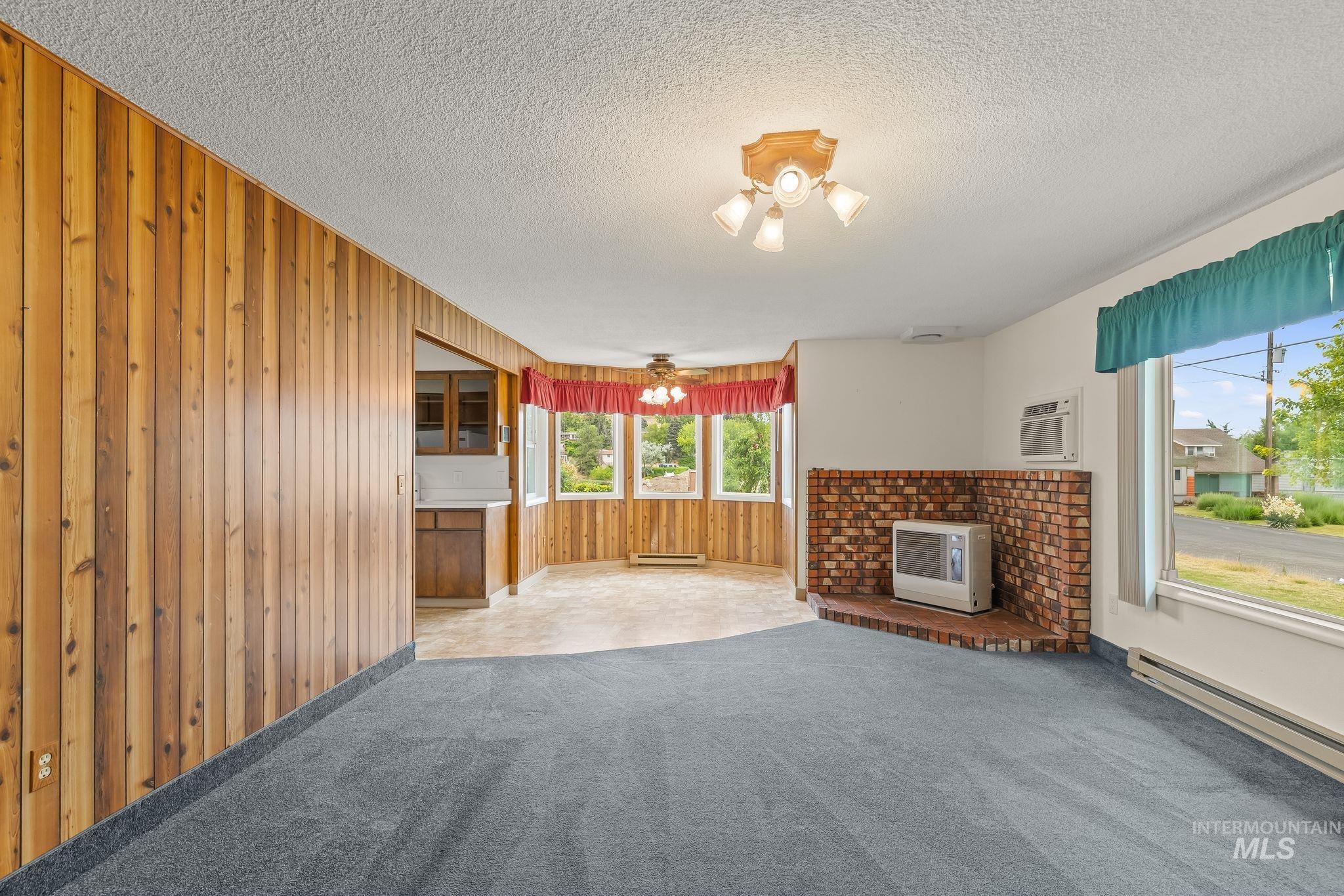 Interior space featuring blue carpeting, a brick-faced hearth, and multiple windows