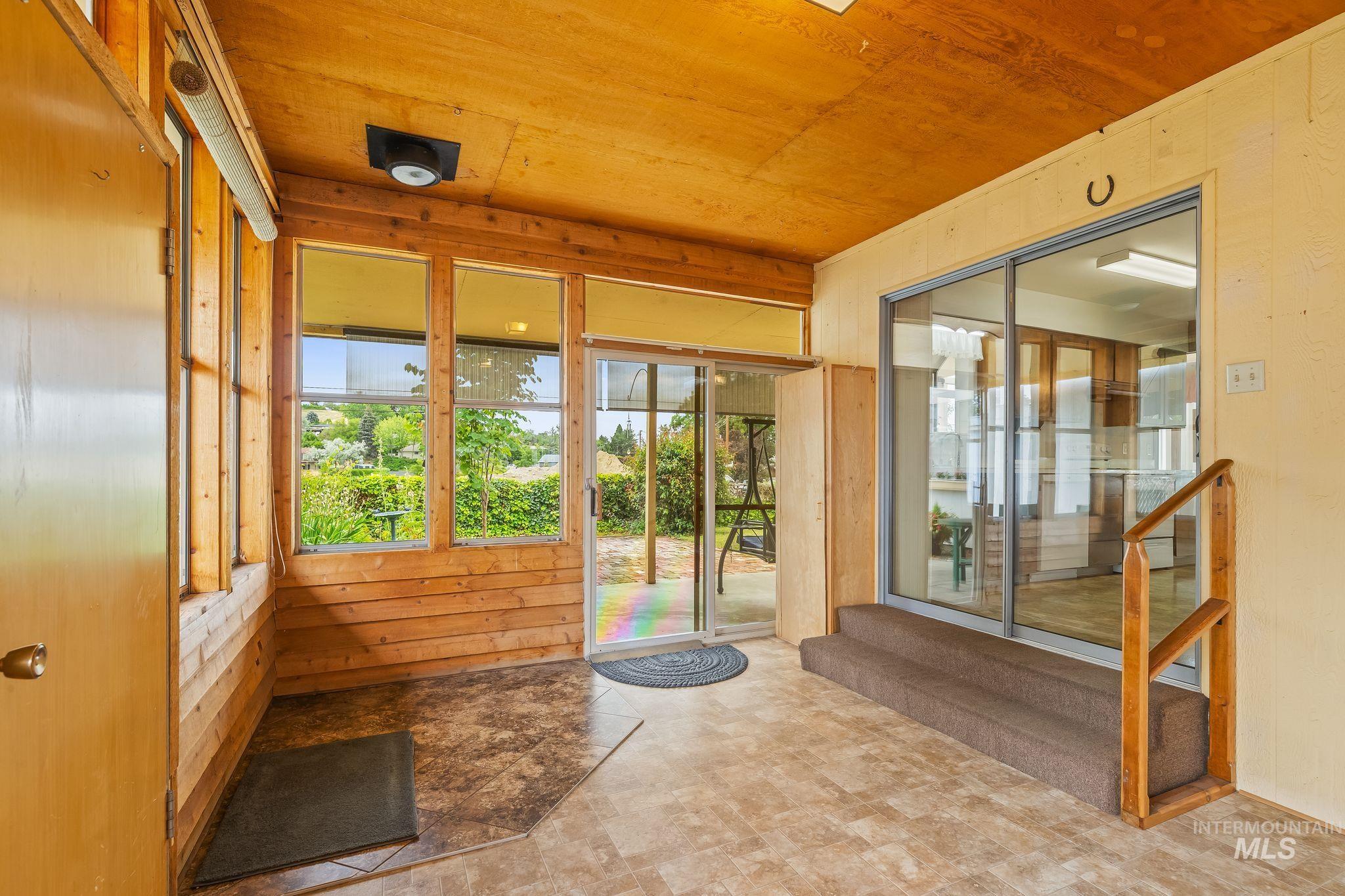 Enclosed porch featuring wood-finish paneling and ceiling, multiple windows, and a sliding glass door
