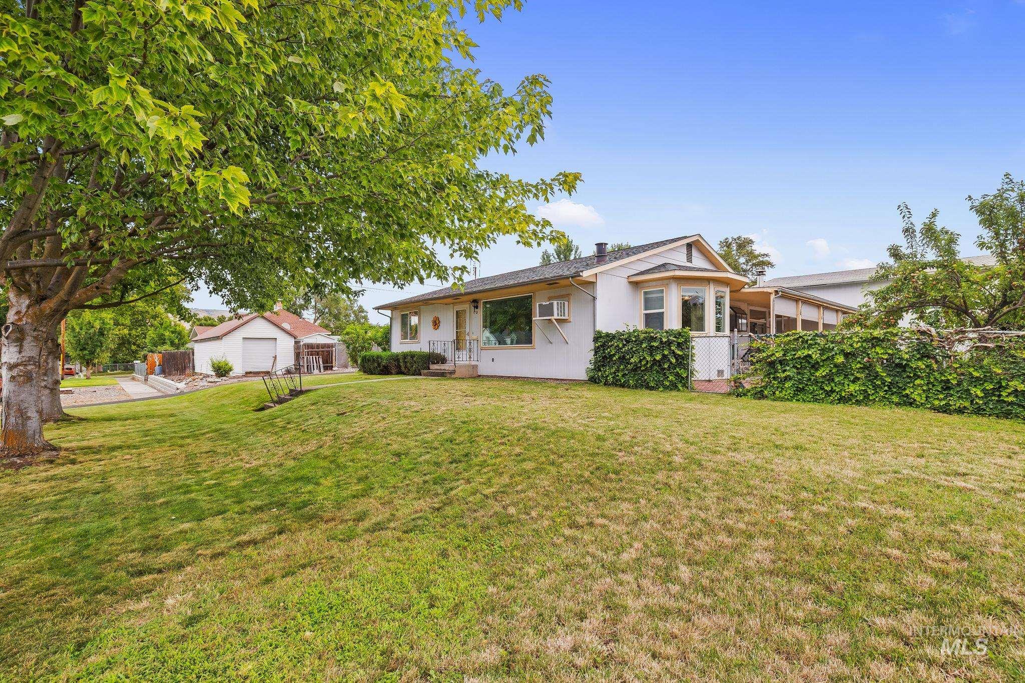 Expansive front lawn with mature trees and a detached garage structure