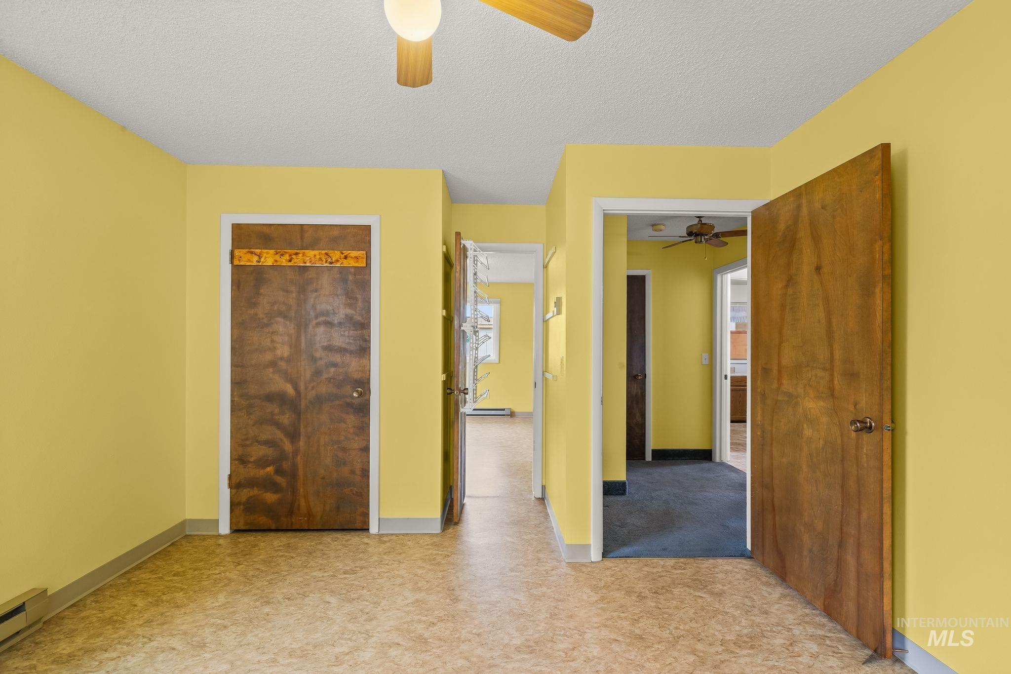 Interior space with light yellow walls, wood-finish flooring, and a ceiling fan