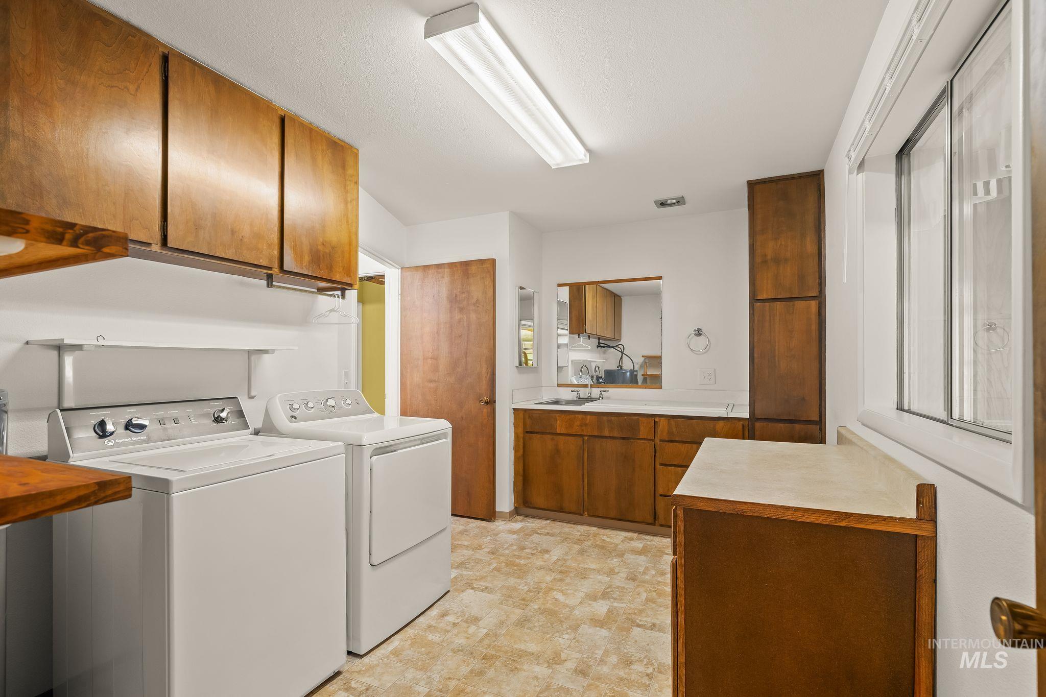 Dedicated utility room featuring wood-finish cabinetry, a built-in sink, and a large window