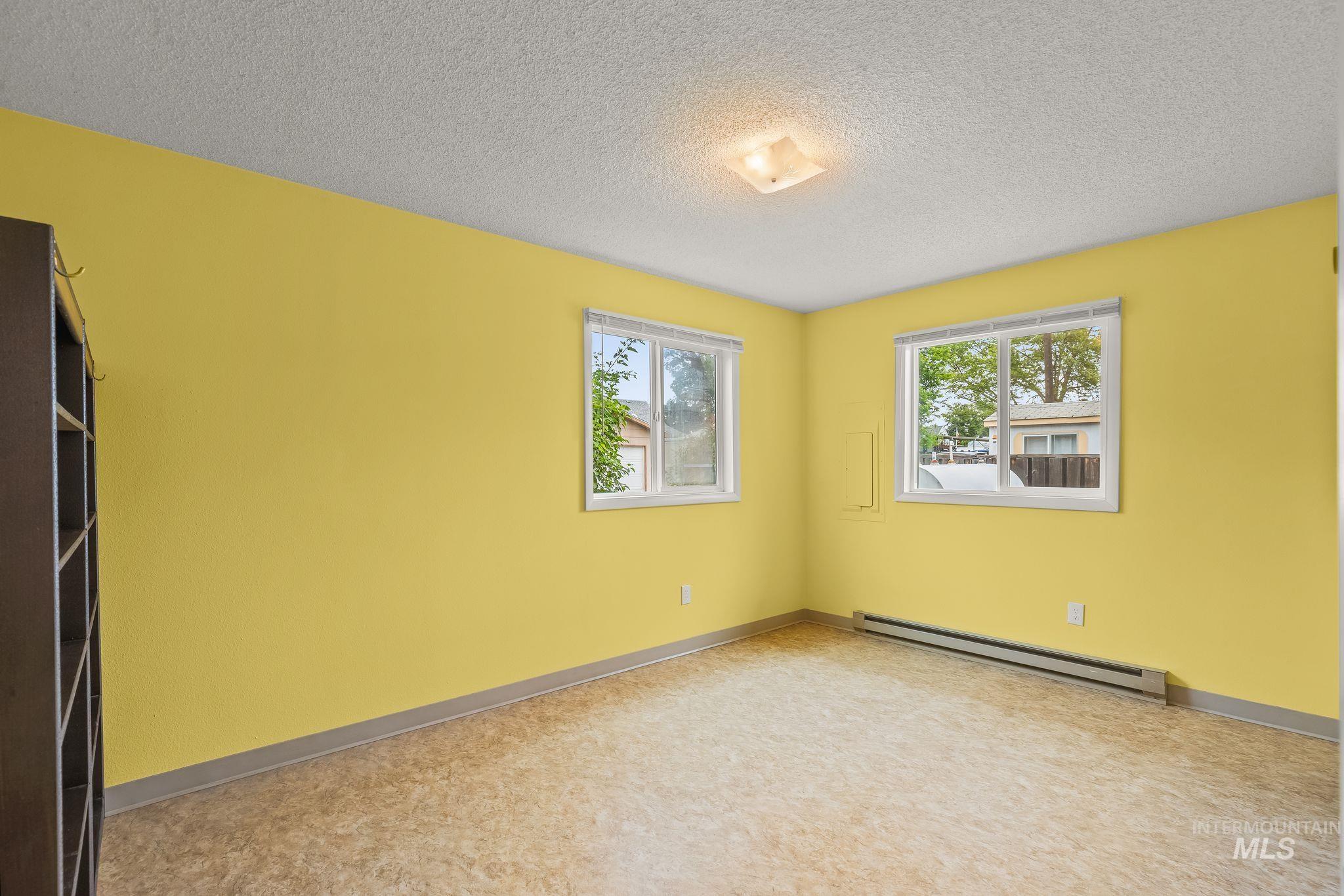 Room featuring light yellow walls, two white-framed windows, and patterned vinyl flooring