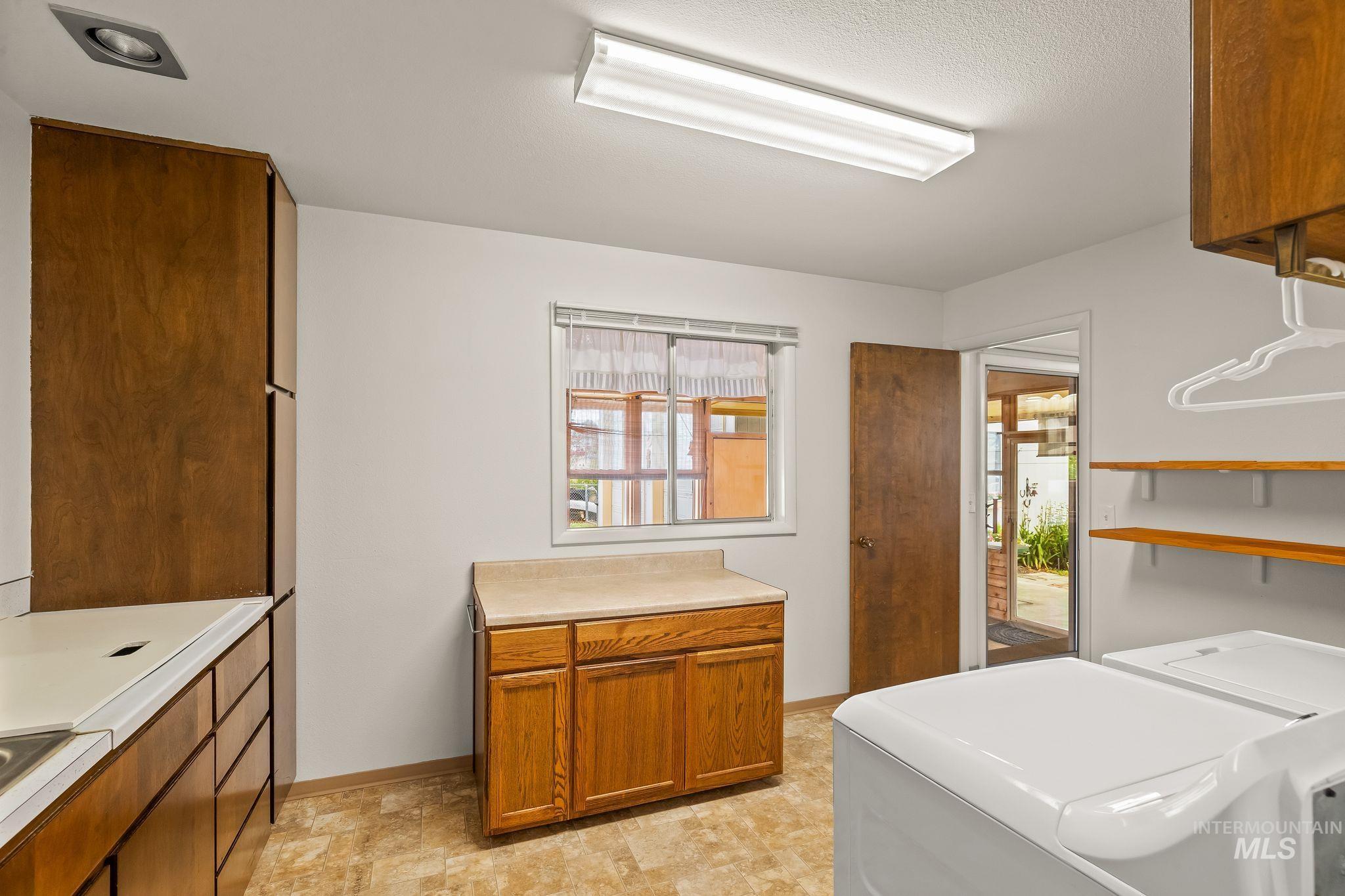 Functional utility room featuring wood-finish cabinetry, a window with natural light, and durable vinyl flooring