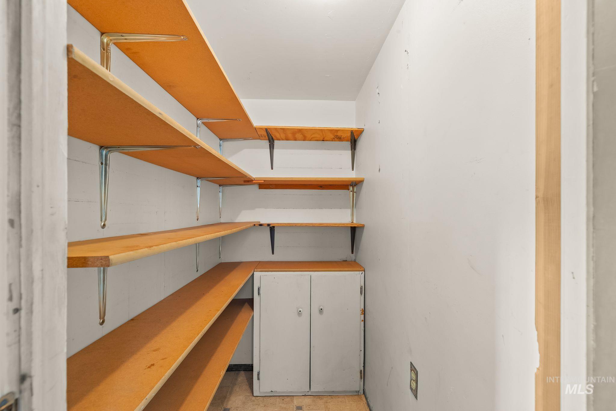 Compact pantry with extensive wood-finish shelving and a built-in lower cabinet