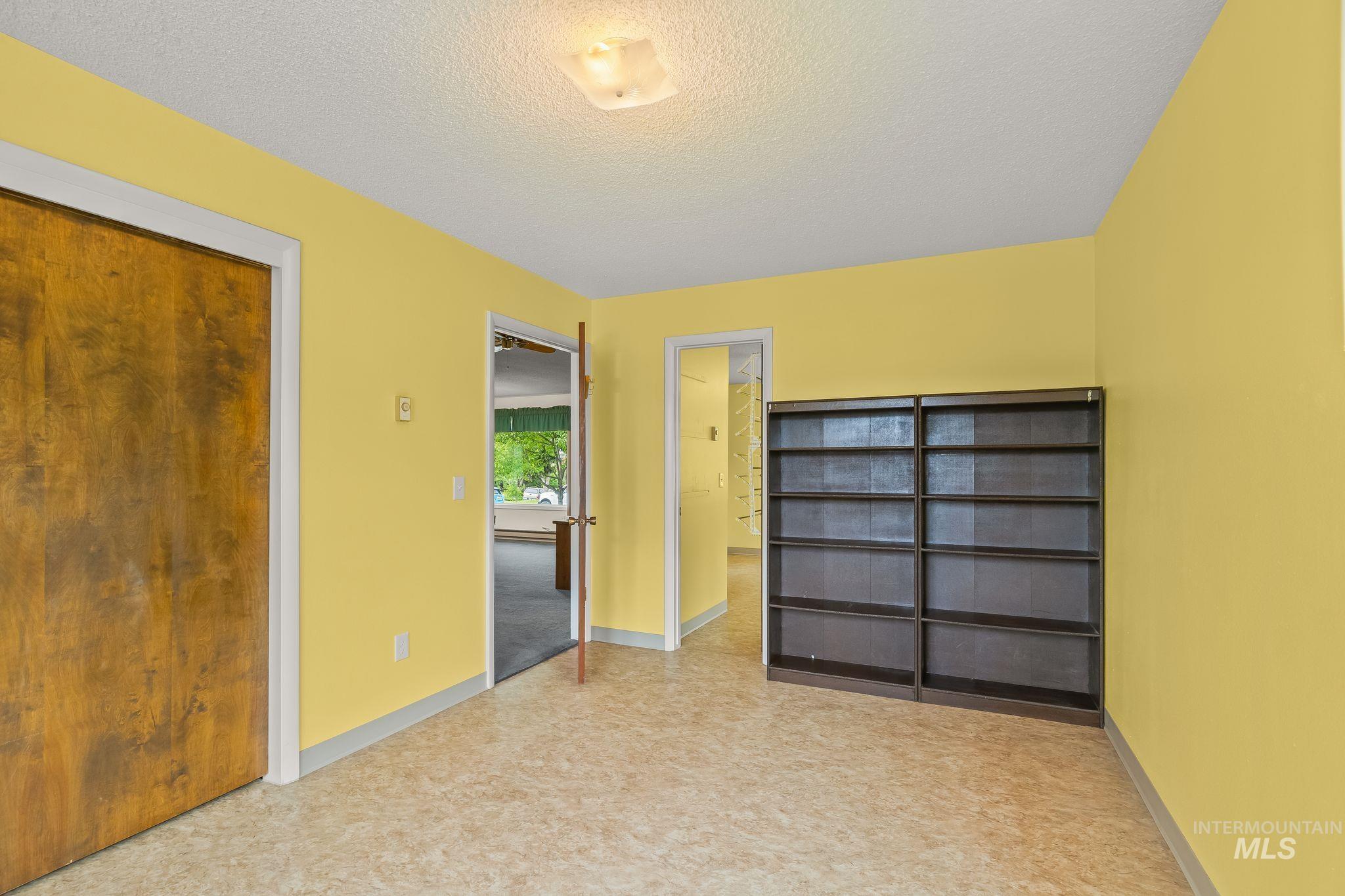 Interior room featuring warm yellow walls, a built-in shelving unit, and patterned vinyl flooring