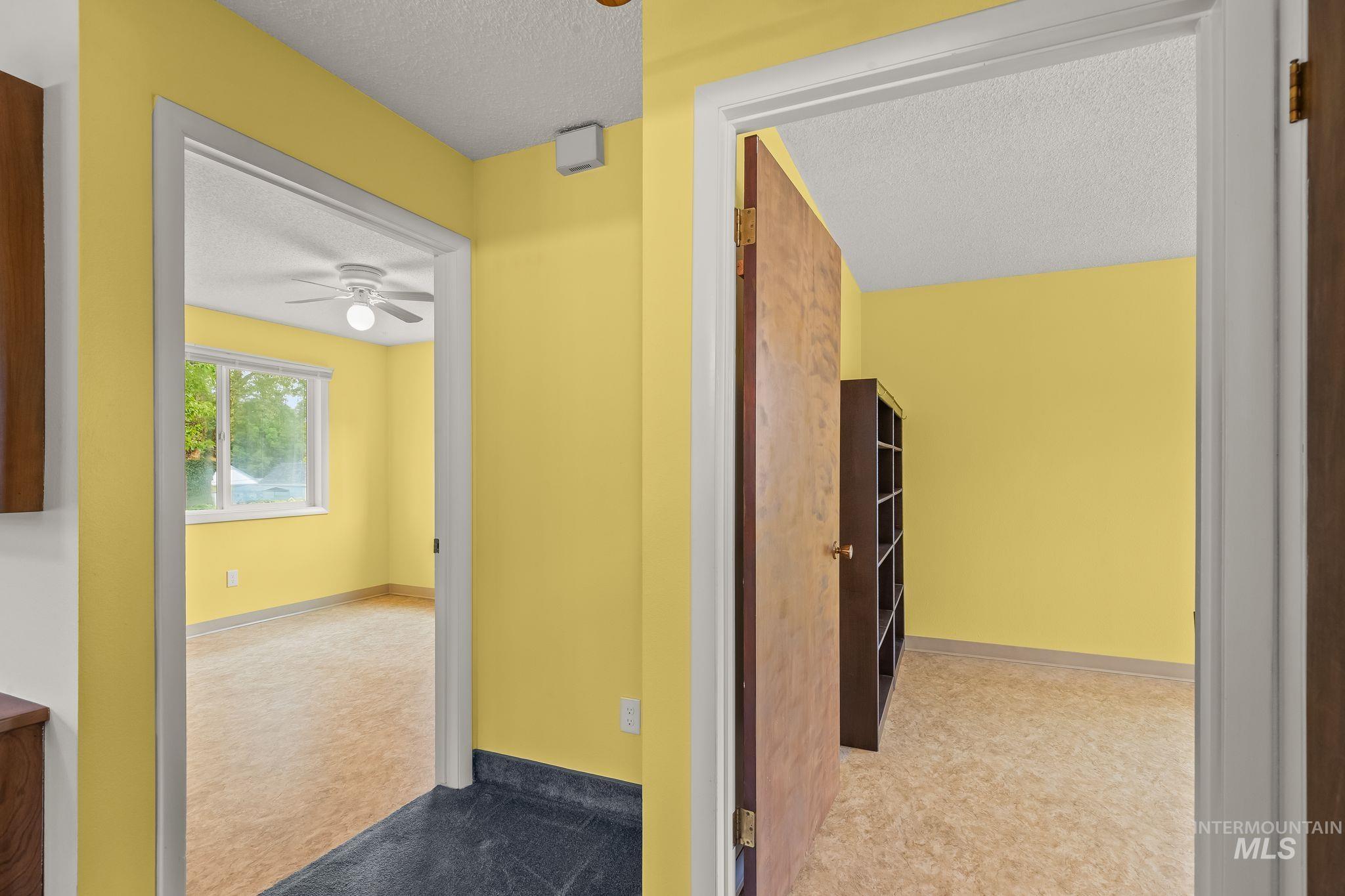 Interior doorways providing access to multiple rooms featuring neutral wall tones, a ceiling fan with integrated lighting, and multiple windows