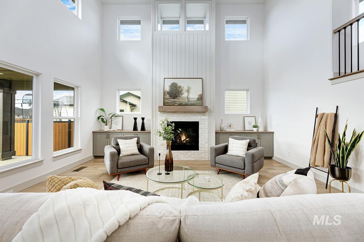 Living area featuring a towering ceiling, a fireplace, and wood finished floors