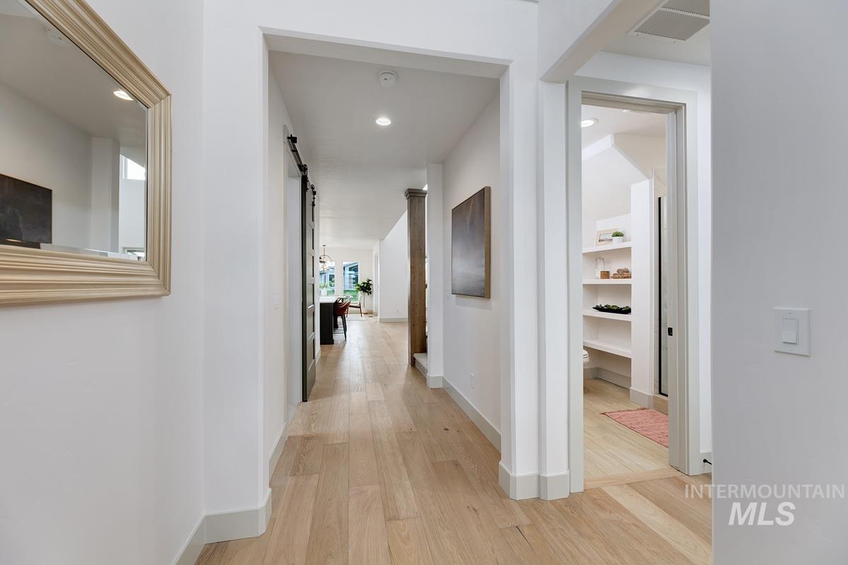 Hall with light wood-style floors, a barn door, and recessed lighting
