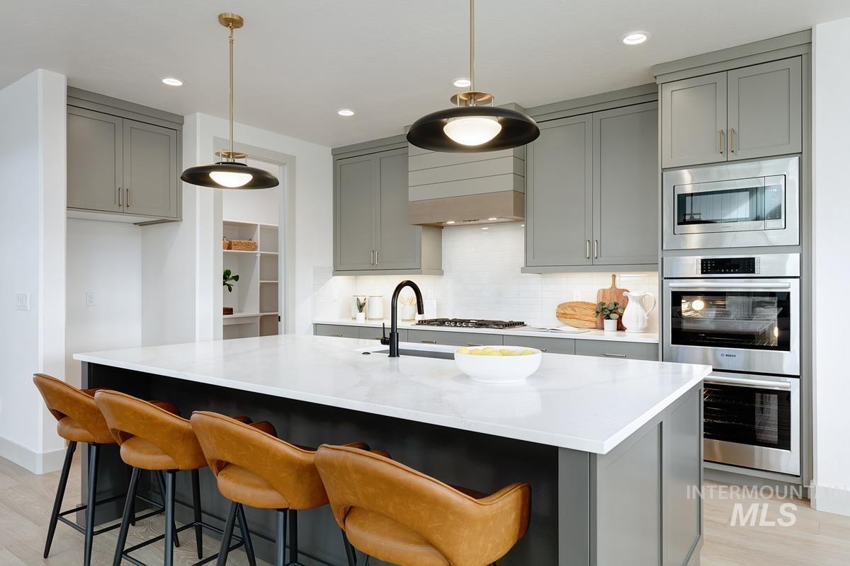 Kitchen with gray cabinetry, light wood-type flooring, tasteful backsplash, pendant lighting, and recessed lighting