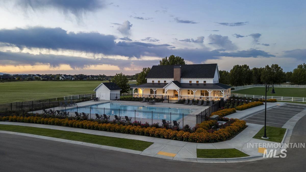 Pool at dusk featuring a patio area, a community pool, and an outdoor structure