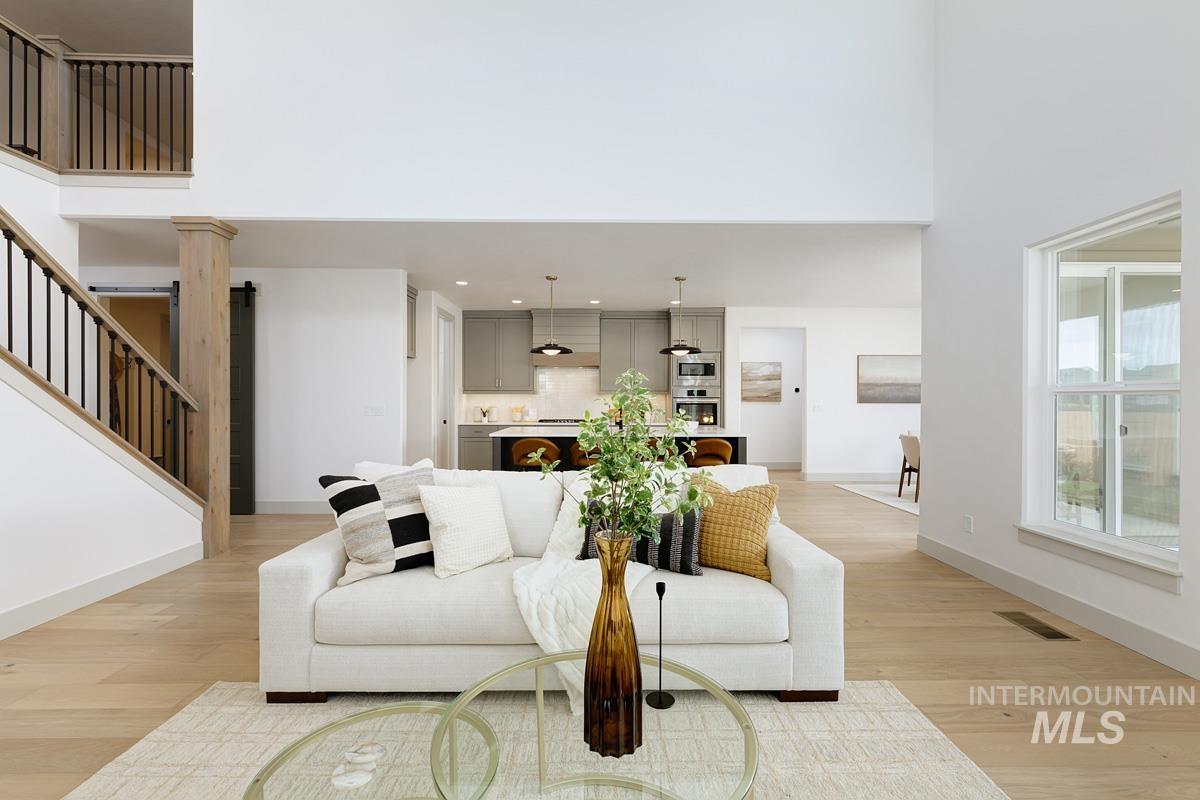 Living room with a high ceiling, light wood-style flooring, and stairway