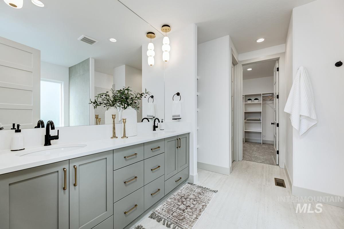 Bathroom with a walk in closet, double vanity, and recessed lighting