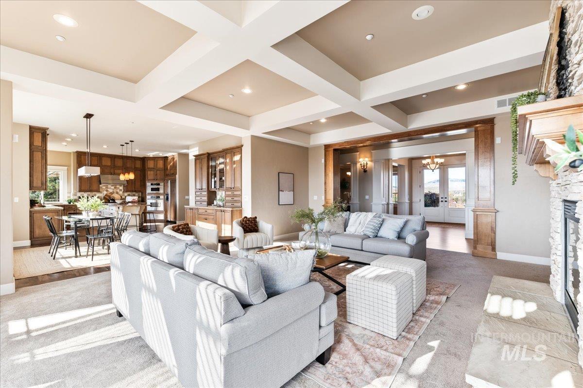 Living room with coffered ceiling, light colored carpet, beam ceiling, a chandelier, and french doors