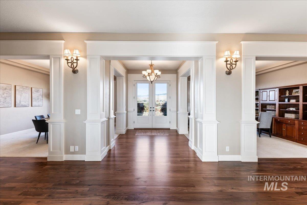 Entryway with decorative columns, walnut wood flooring, and french doors