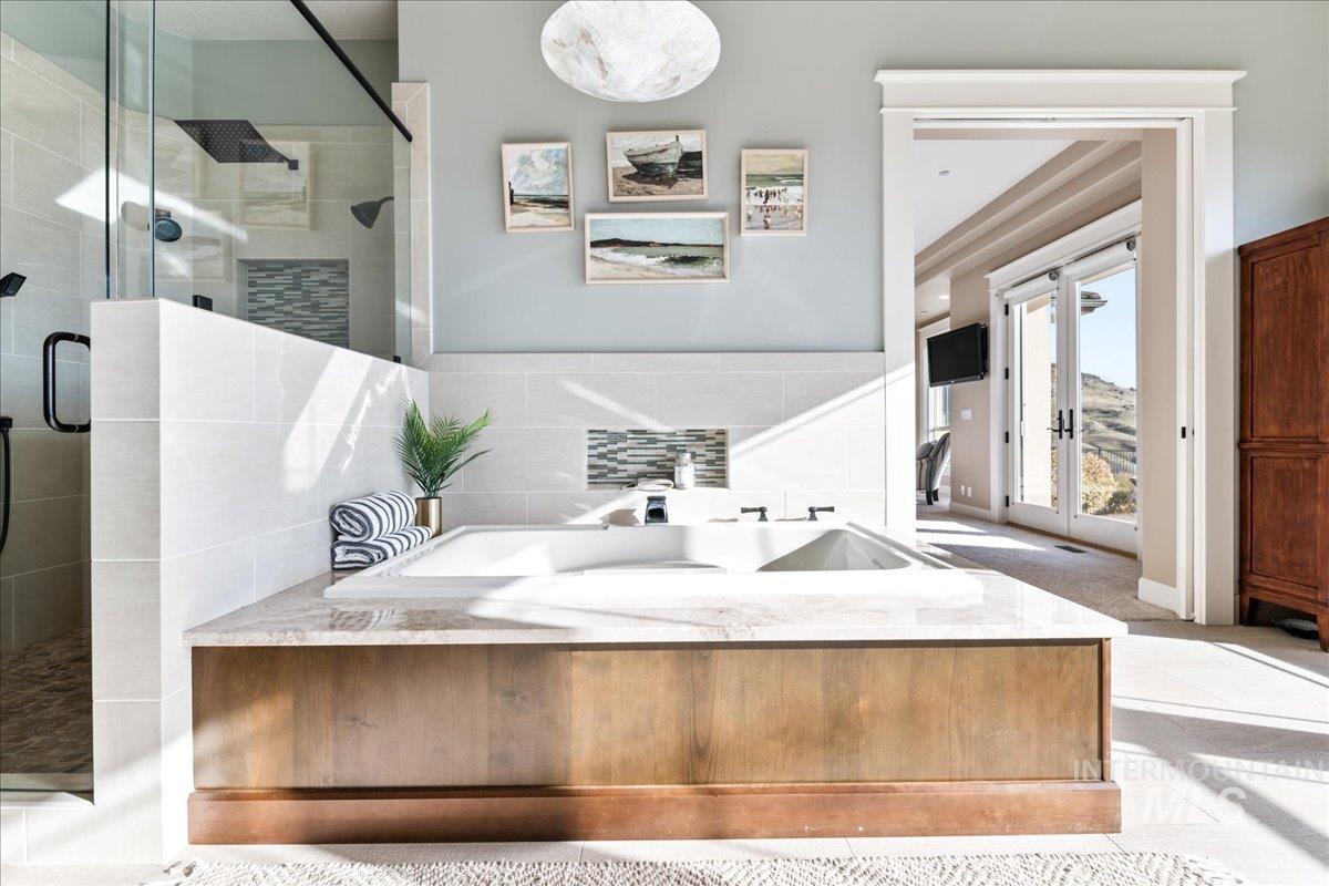 Full bathroom with a bath, a shower stall, french doors, carpet, and tile walls