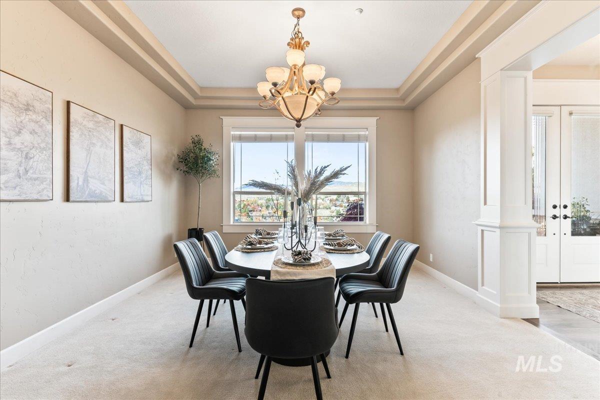 Dining room with a tray ceiling, ornate columns and a chandelier