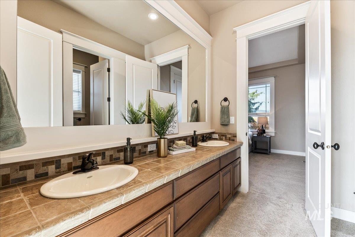 Full bathroom with light colored carpet, double vanity, decorative backsplash, and recessed lighting
