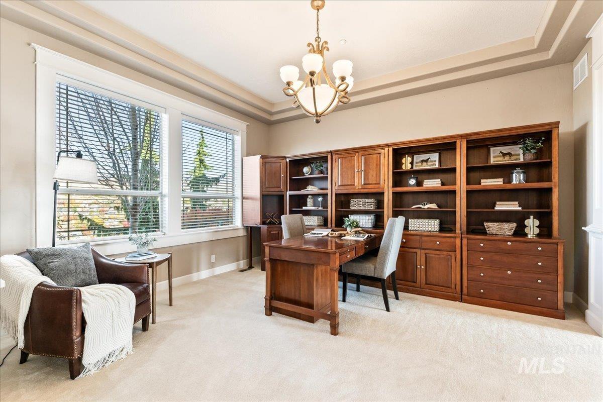 Office area with a raised ceiling, light carpet, and a chandelier