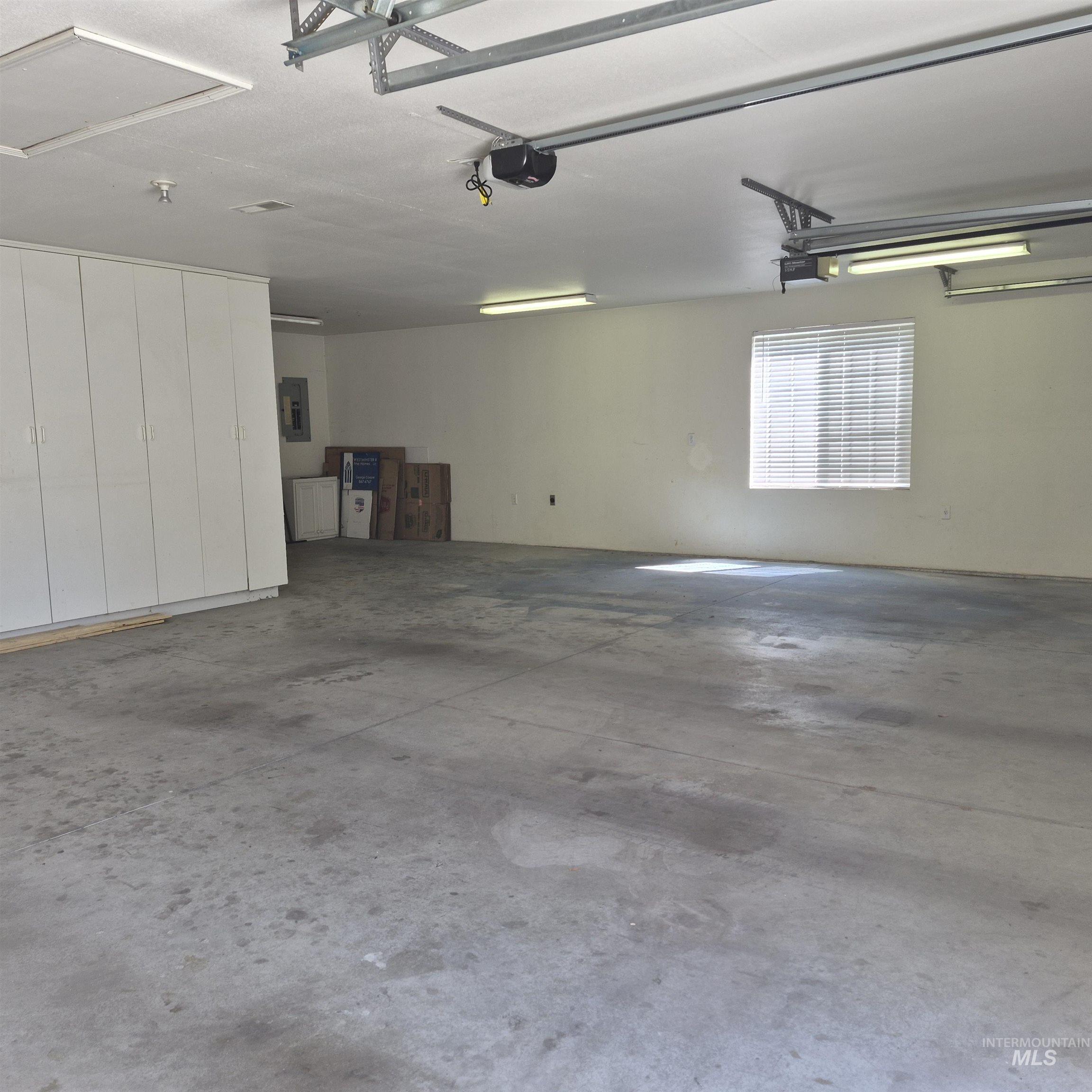 Extra deep, featuring a concrete floor, built-in storage cabinetry, fluorescent lighting, and a window with blinds