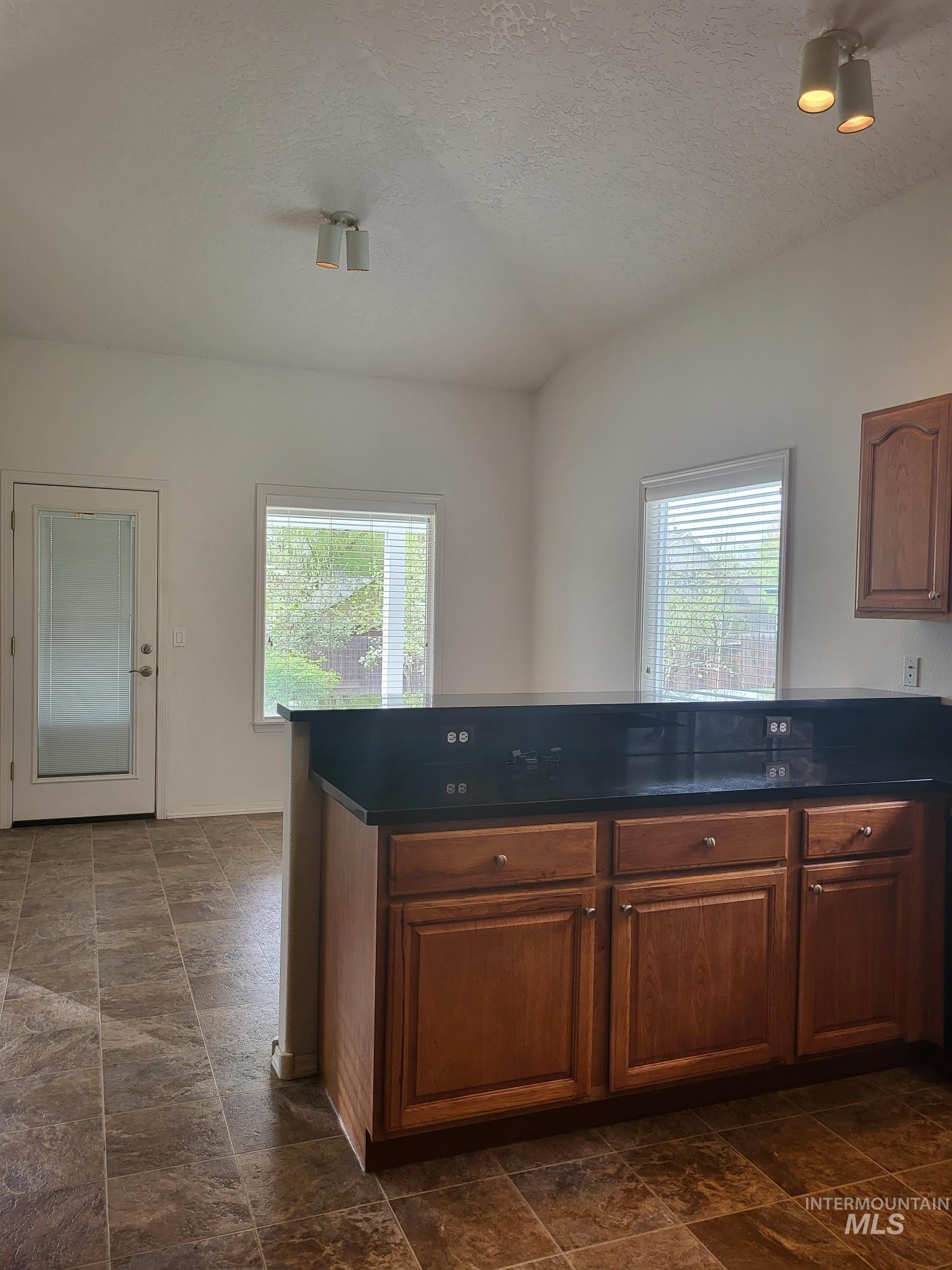 Kitchen featuring a dark countertop, wood-finish cabinetry and the informal dining space.