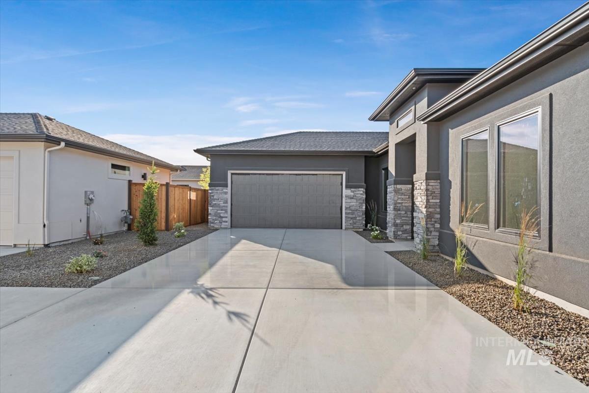 View of side of home with stone siding, driveway, stucco siding, and an attached garage