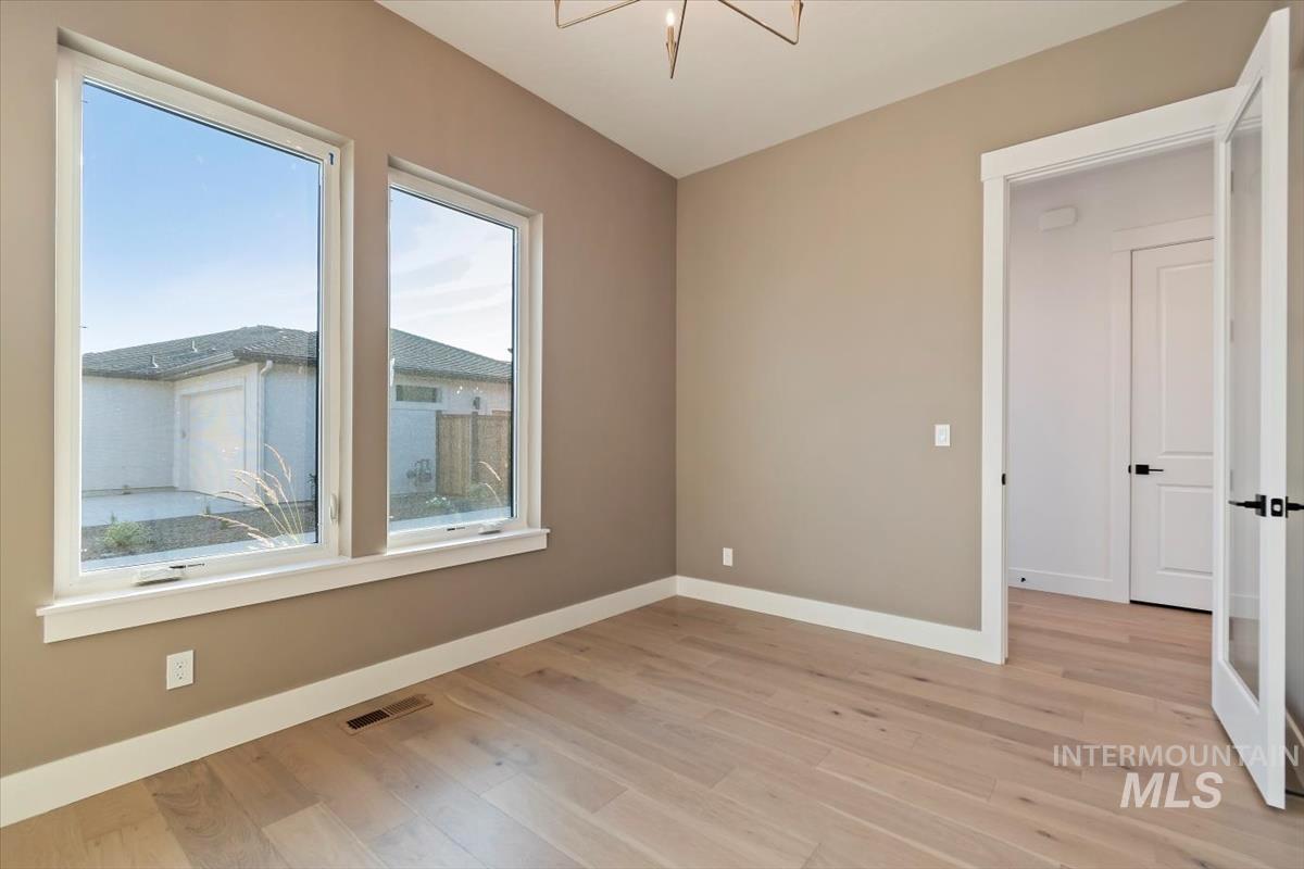 Unfurnished room featuring light wood-style floors and a chandelier