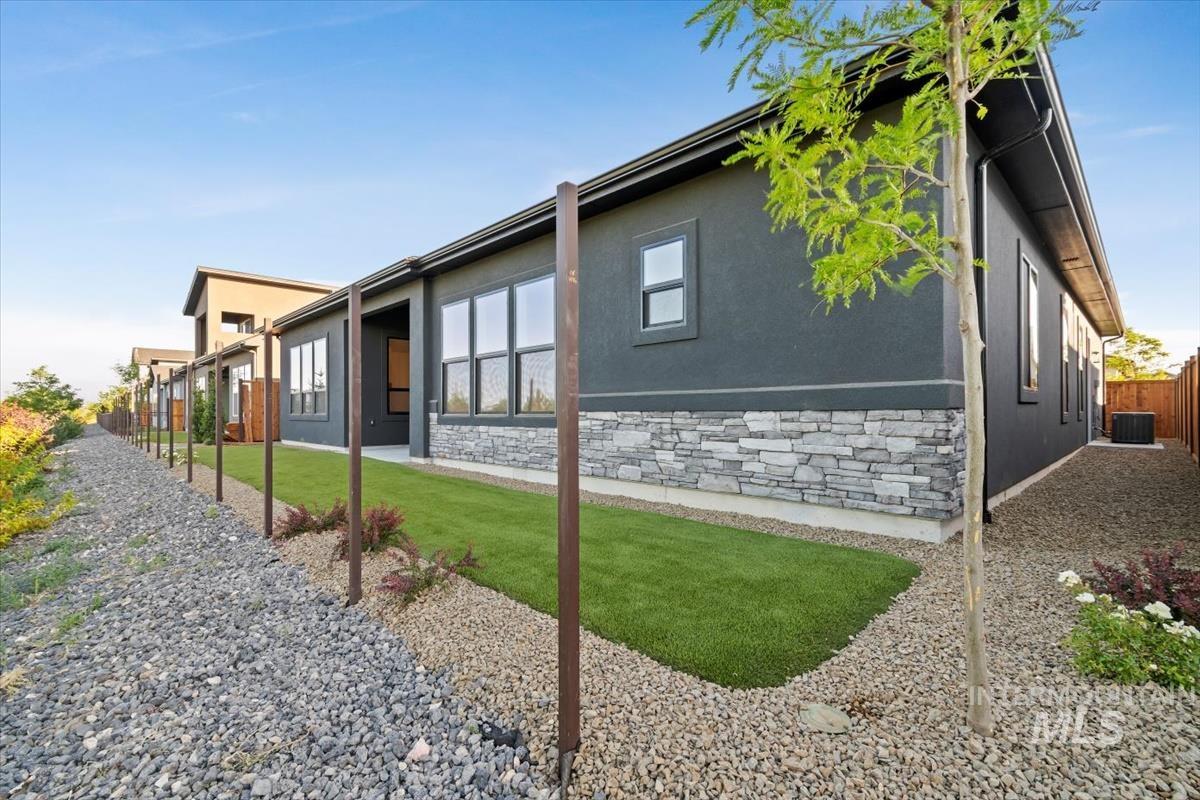 View of side of property with stone siding, stucco siding, and a patio area