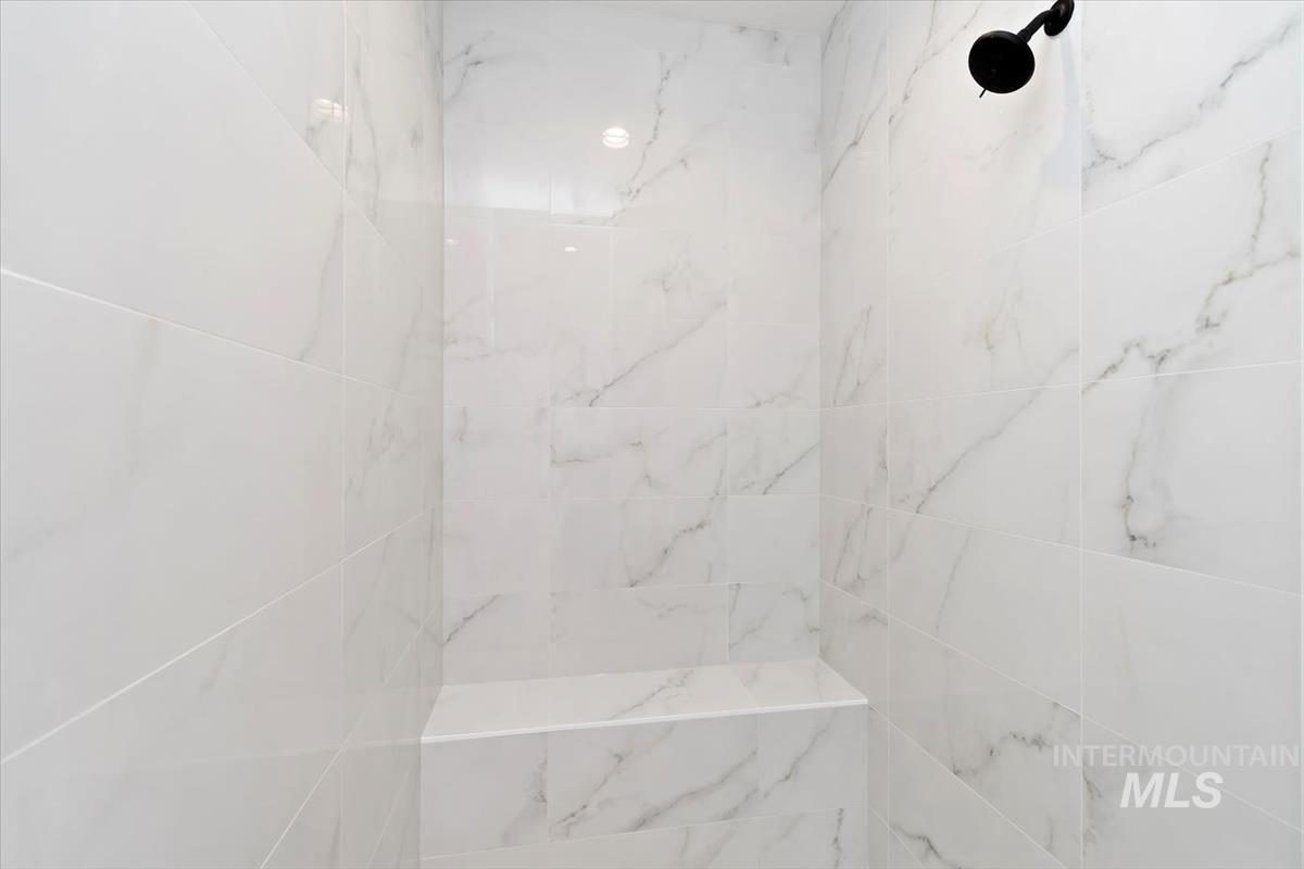 Full bath with a marble finish shower