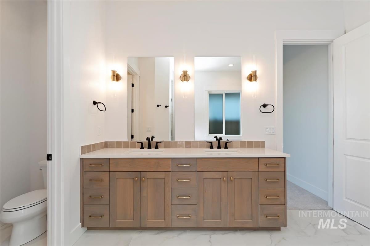 Full bathroom featuring double vanity and light marble finish floors
