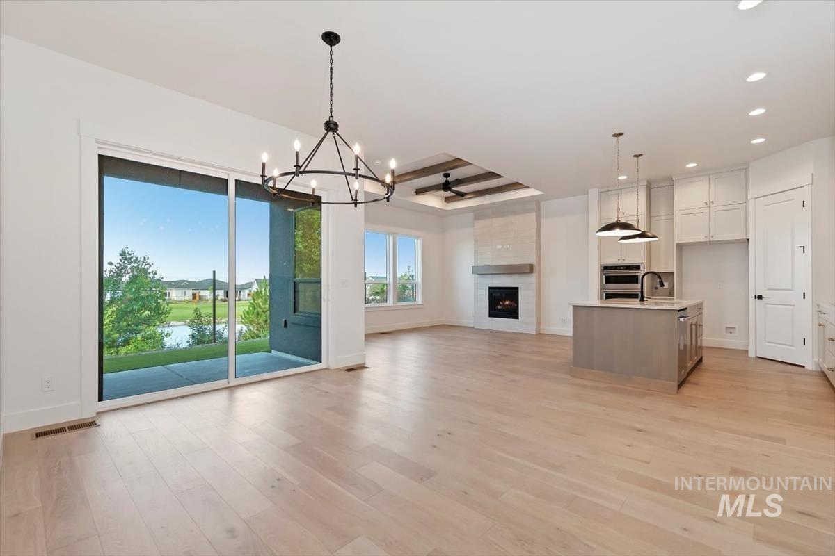 Unfurnished living room featuring a chandelier, a fireplace, light wood-style flooring, and recessed lighting