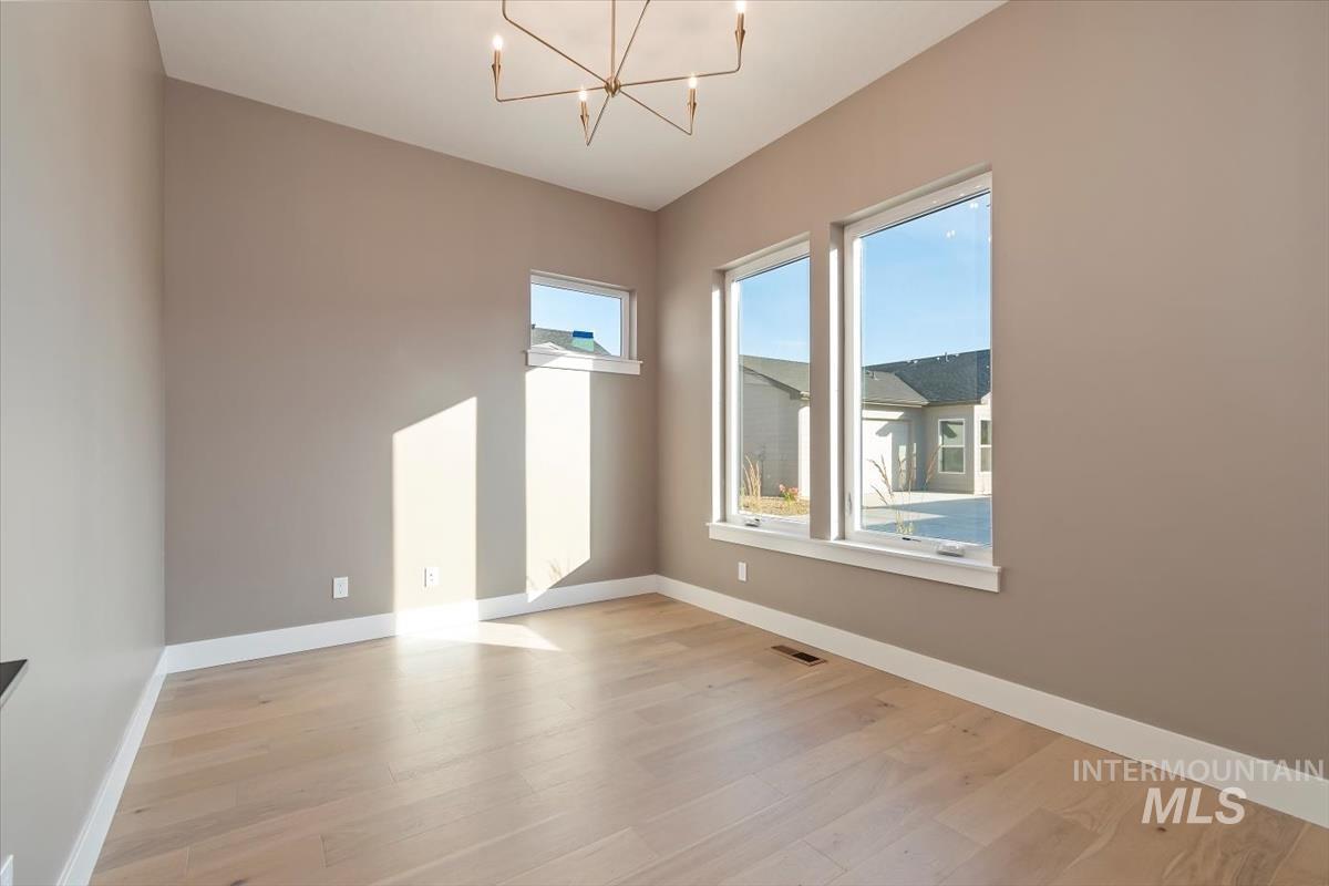 Spare room featuring light wood-type flooring and a chandelier